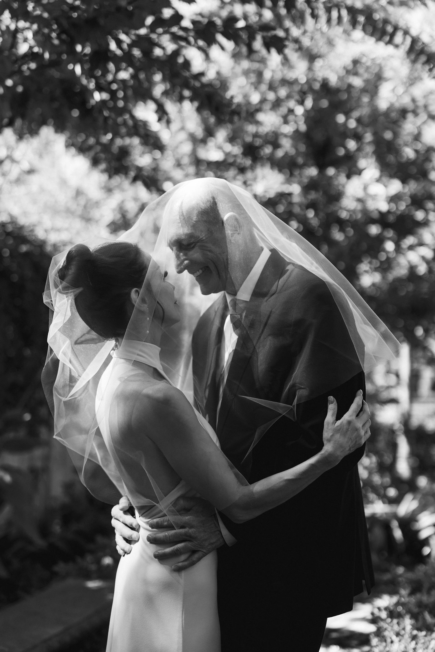 Artistic black and white wedding photos with flowing veil creating romantic silhouettes.