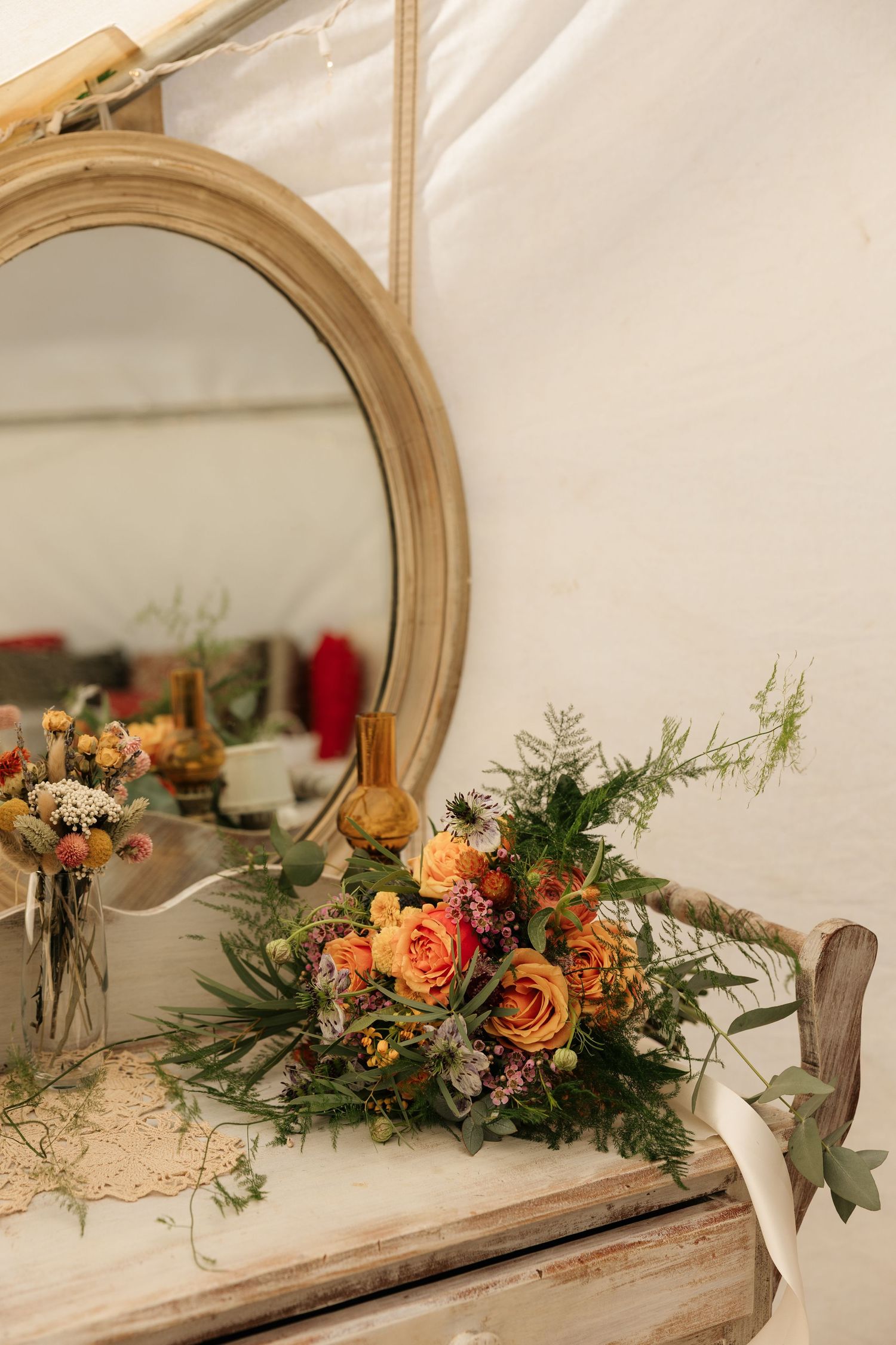 A romantic wedding floral arrangement with peach roses reflects in an antique gold-framed mirror.