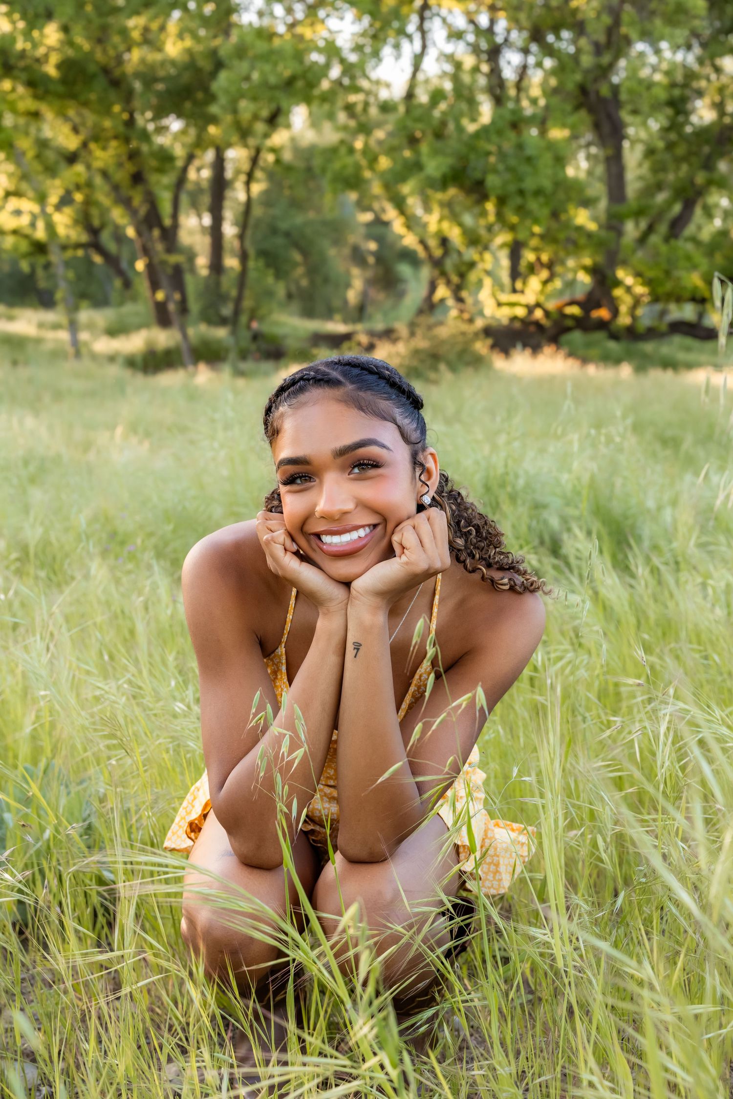 Woman lying in tall grass field during golden hour sunset.