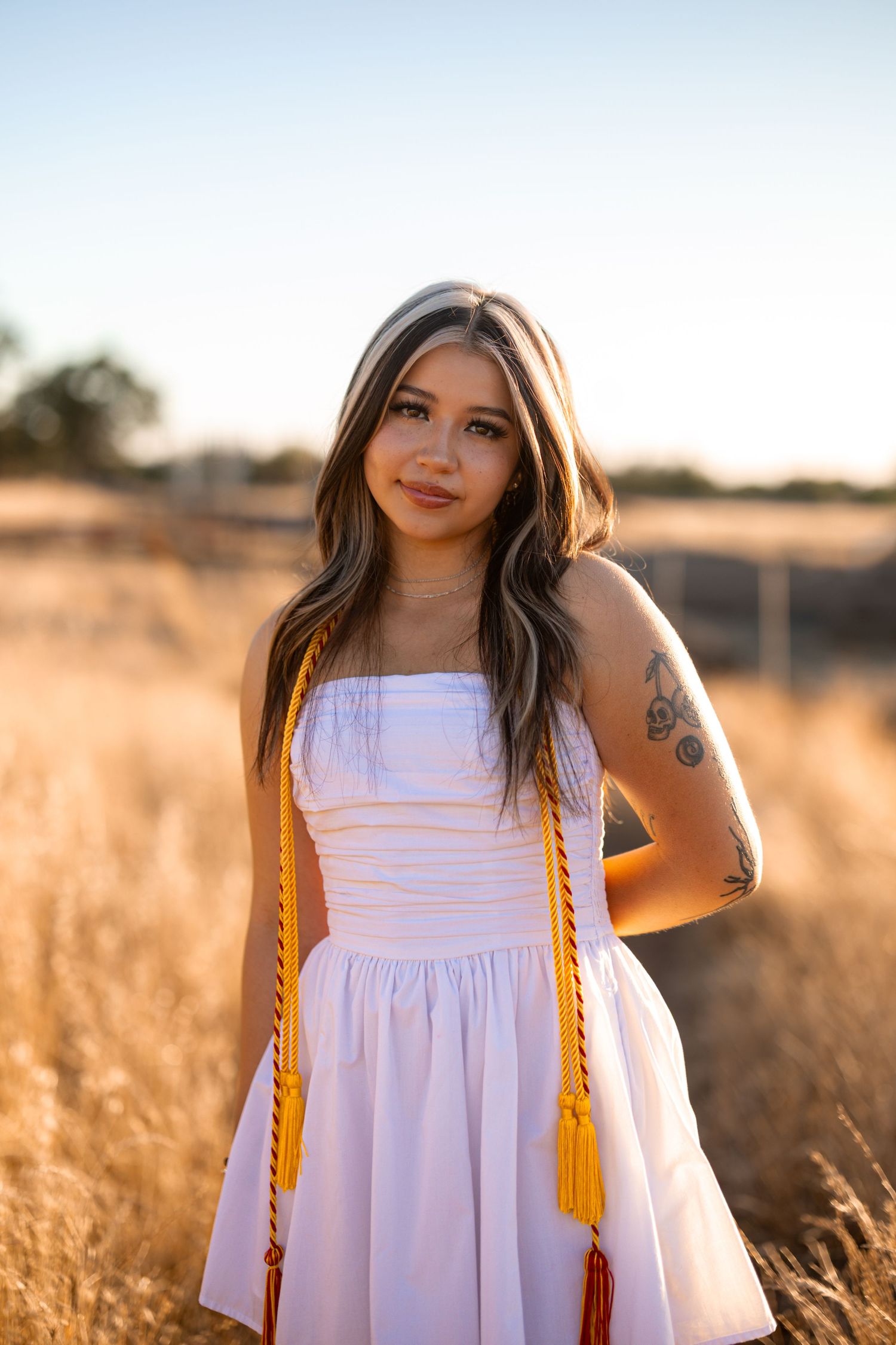 A white dress glows in golden sunlight amidst a wheat field at sunset.