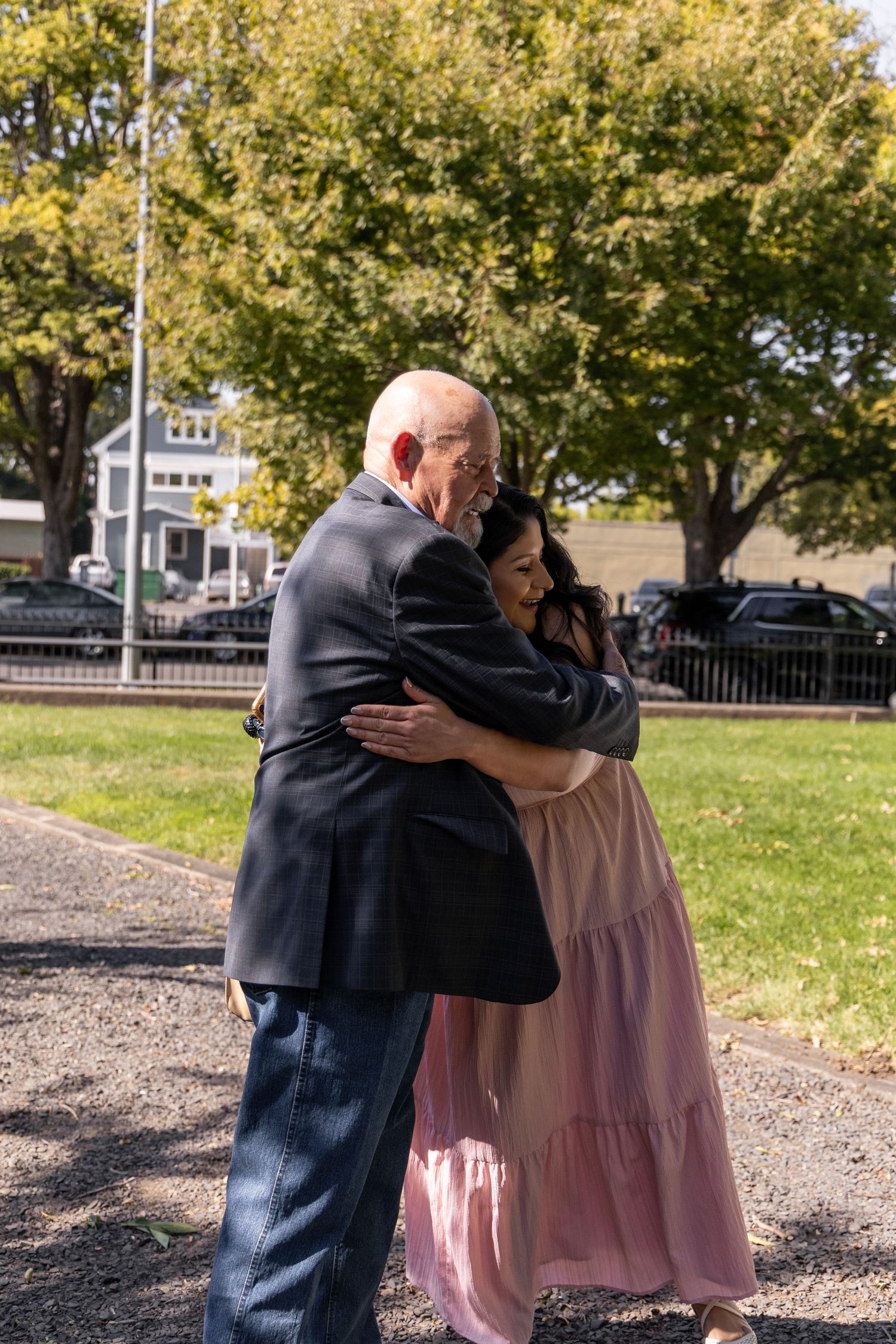 Emotional embrace captured in outdoor setting with autumn trees in background.