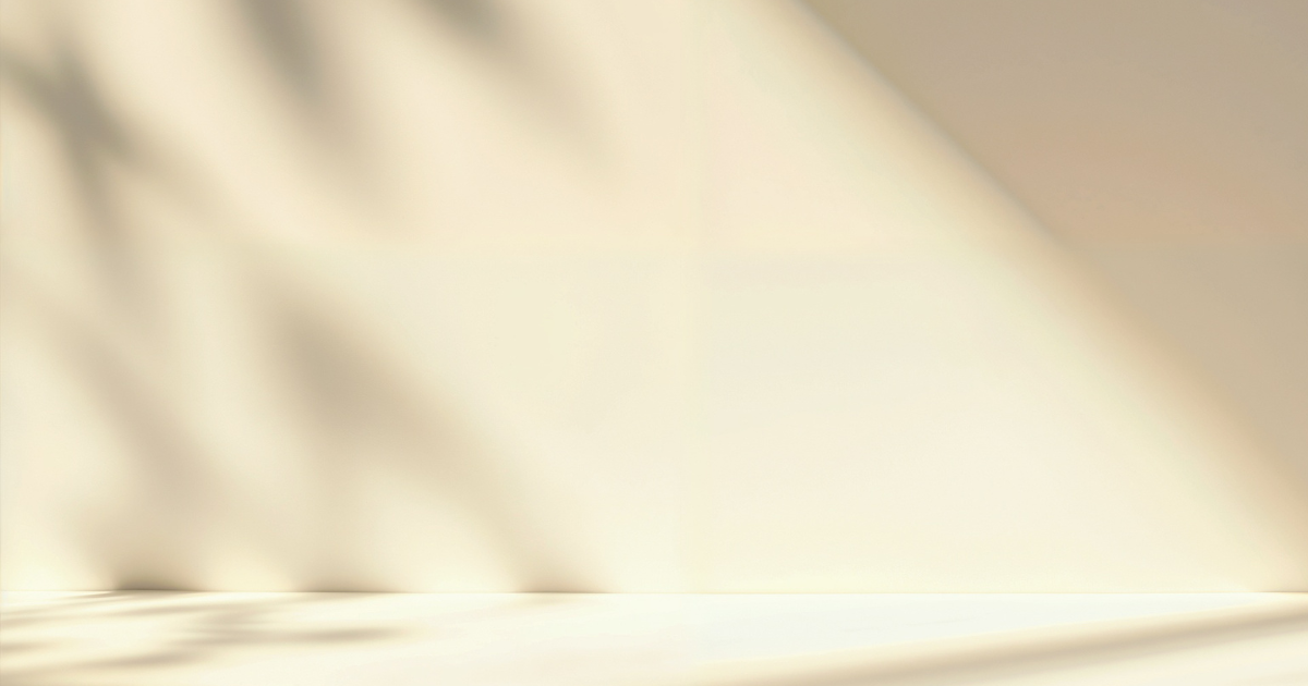Minimalist beige studio background with soft natural window light and shadow overlay for product display.