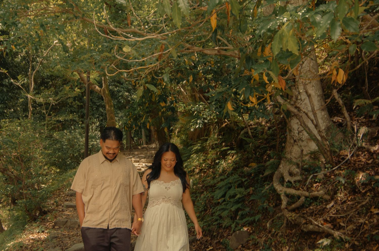 Happy couple walking hand in hand along a lush tropical forest path together.