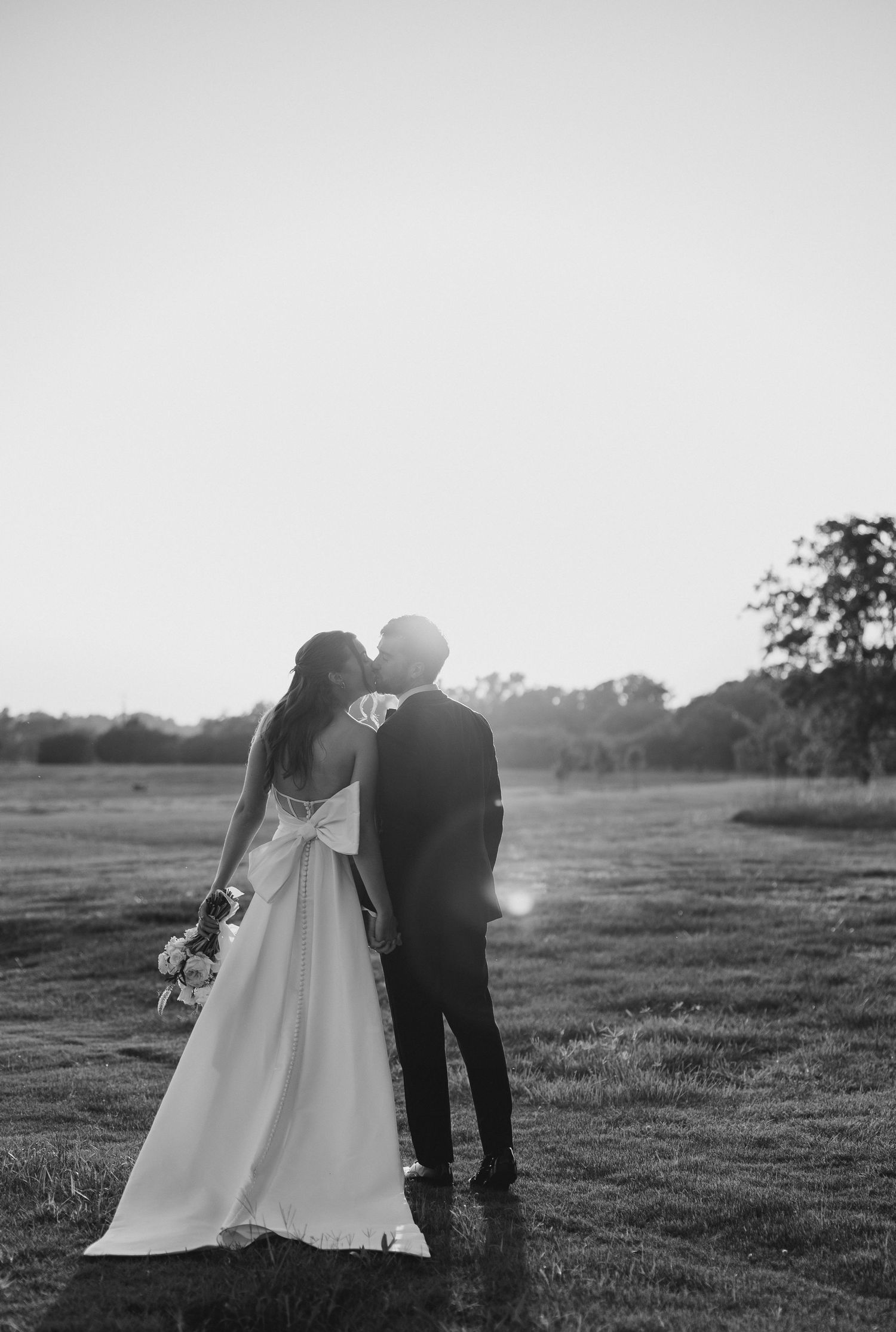 A romantic black and white photo series shows a couple in wedding attire sharing intimate moments in an outdoor field at Chandelier Farms.