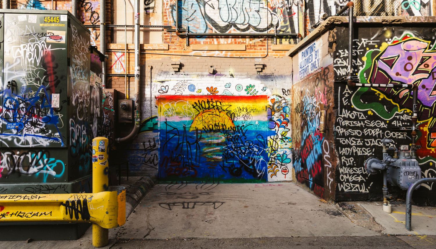 Urban alley covered in colorful graffiti art and street murals.