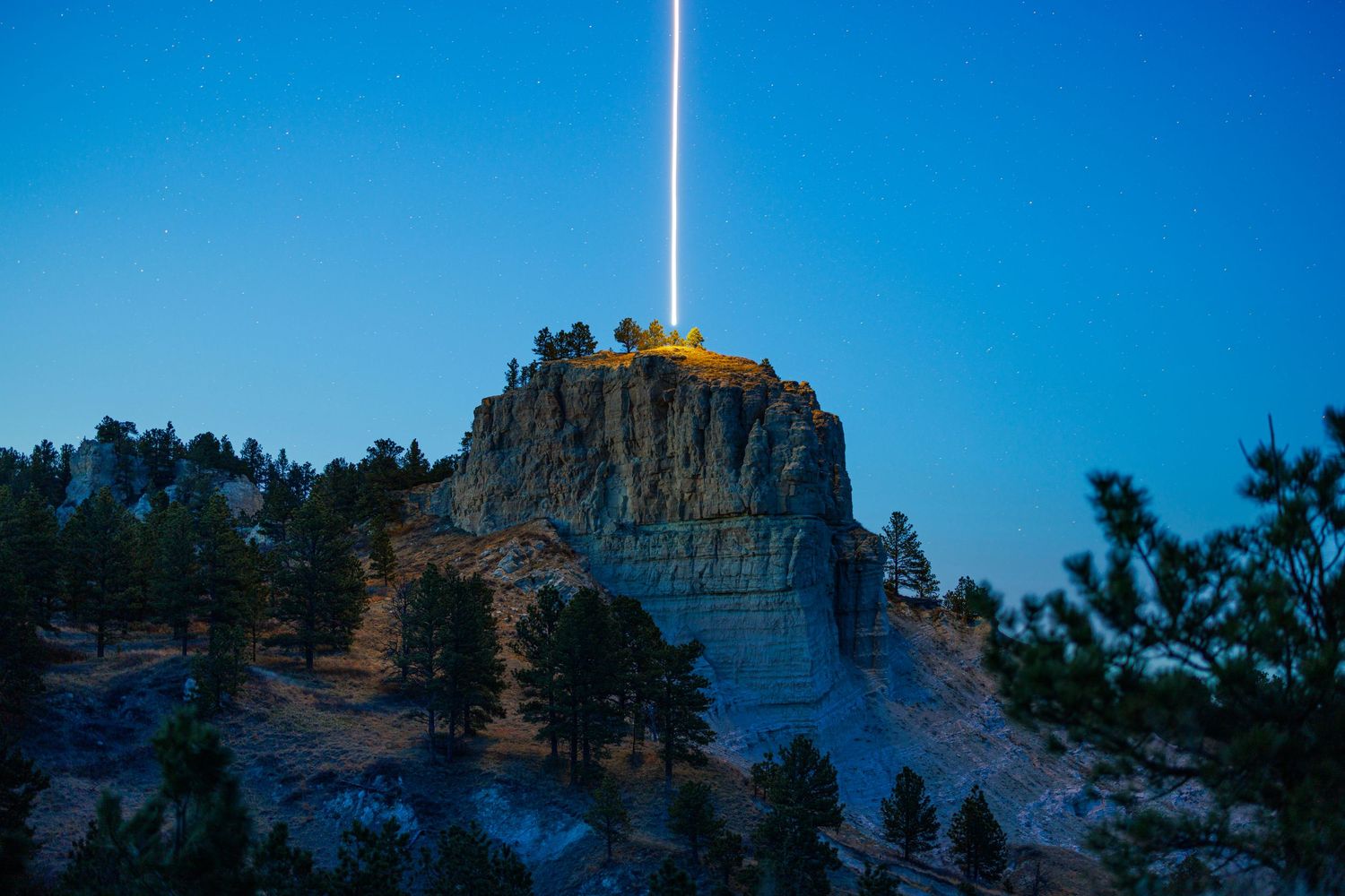 Panoramic view of Mount Rushmore National Memorial at dusk with dramatic blue sky and illuminated rock faces.