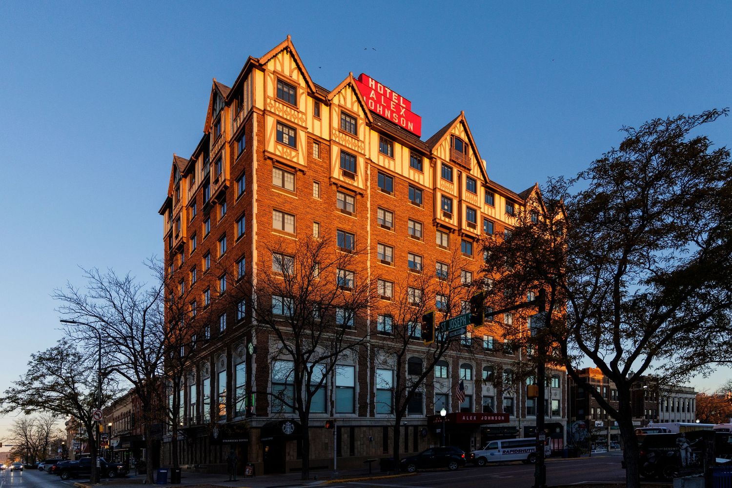 Panoramic view of a brick apartment building complex with retail spaces at sunset.