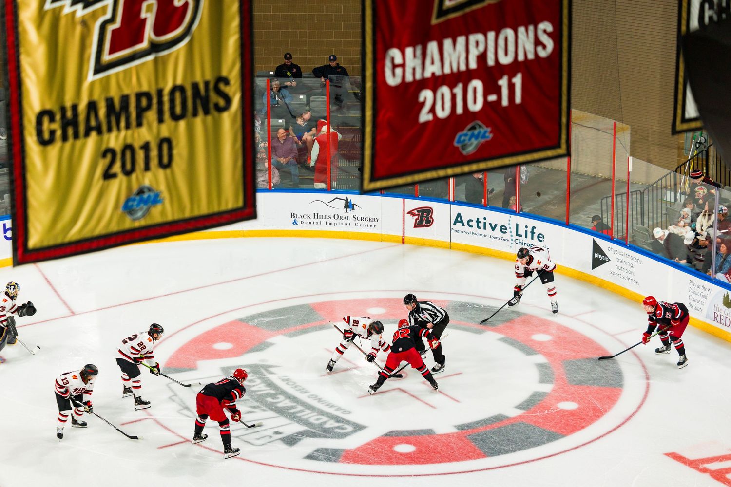 Hockey players compete on ice during a game with championship banners visible in the arena background.