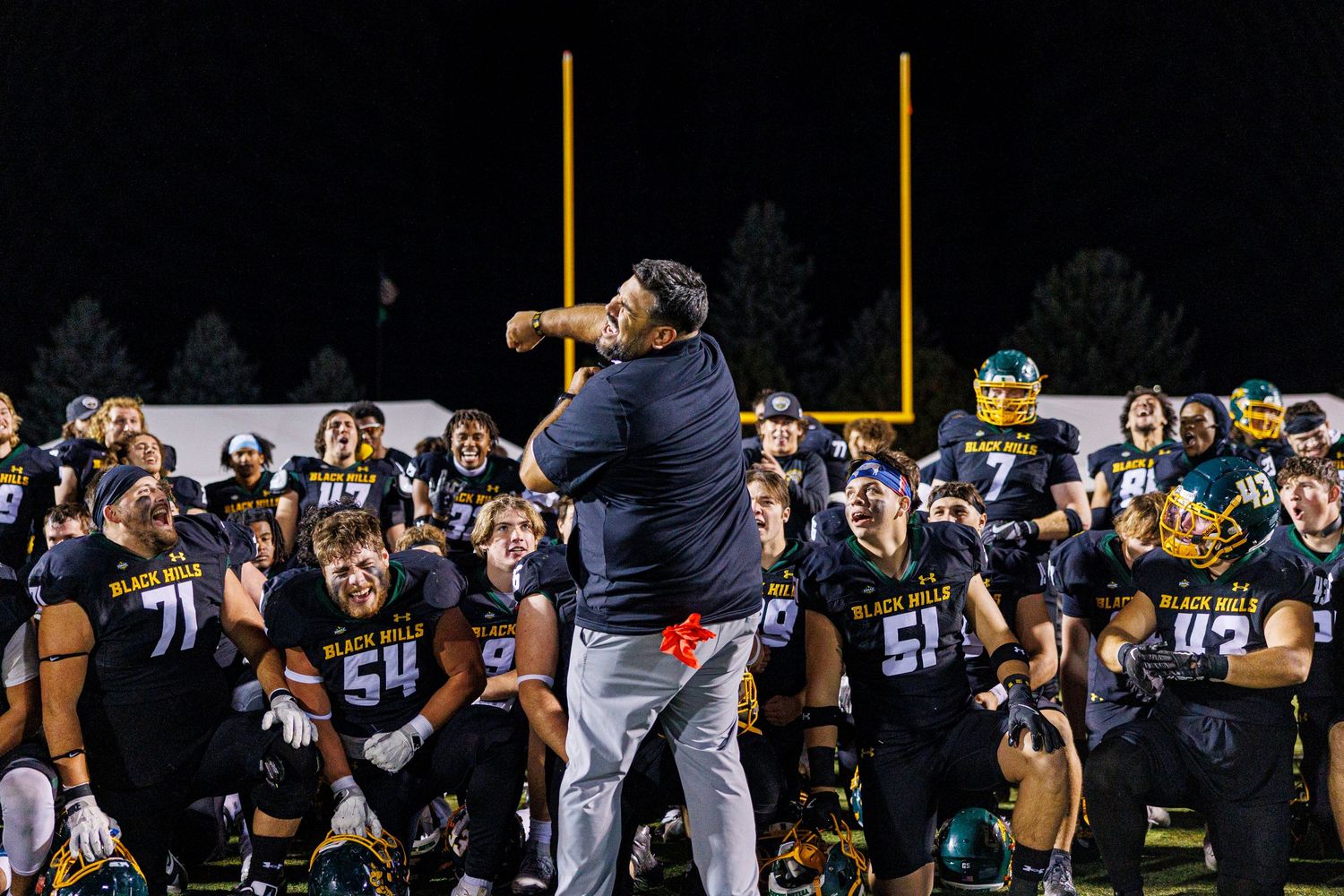 Football players lined up on the field during a night game under stadium lights.