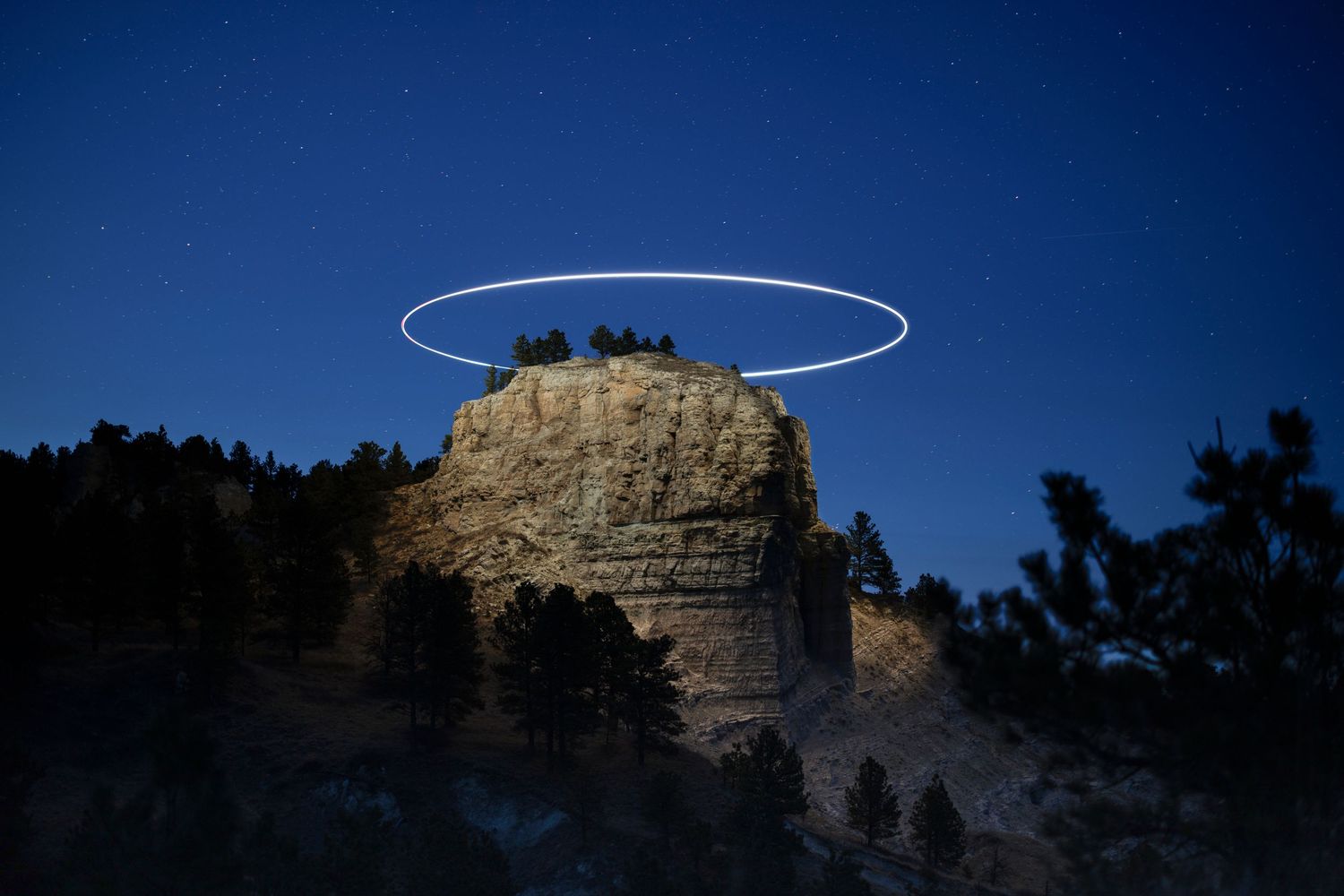 Mysterious ring of light floating above mountain peak at twilight.