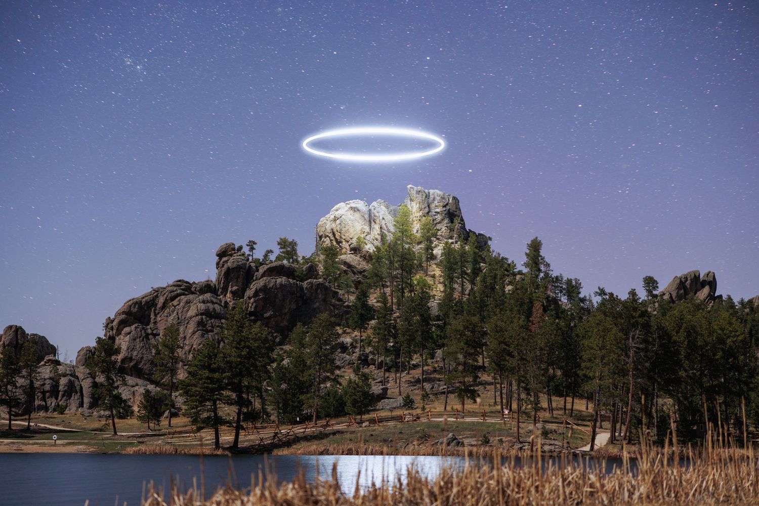 Luminous ring hovers above mountain landscape during starlit evening.