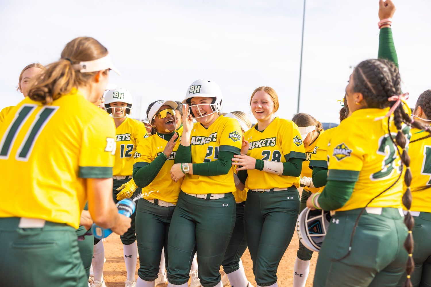 Athletes in yellow and green uniforms celebrating on a sports field.