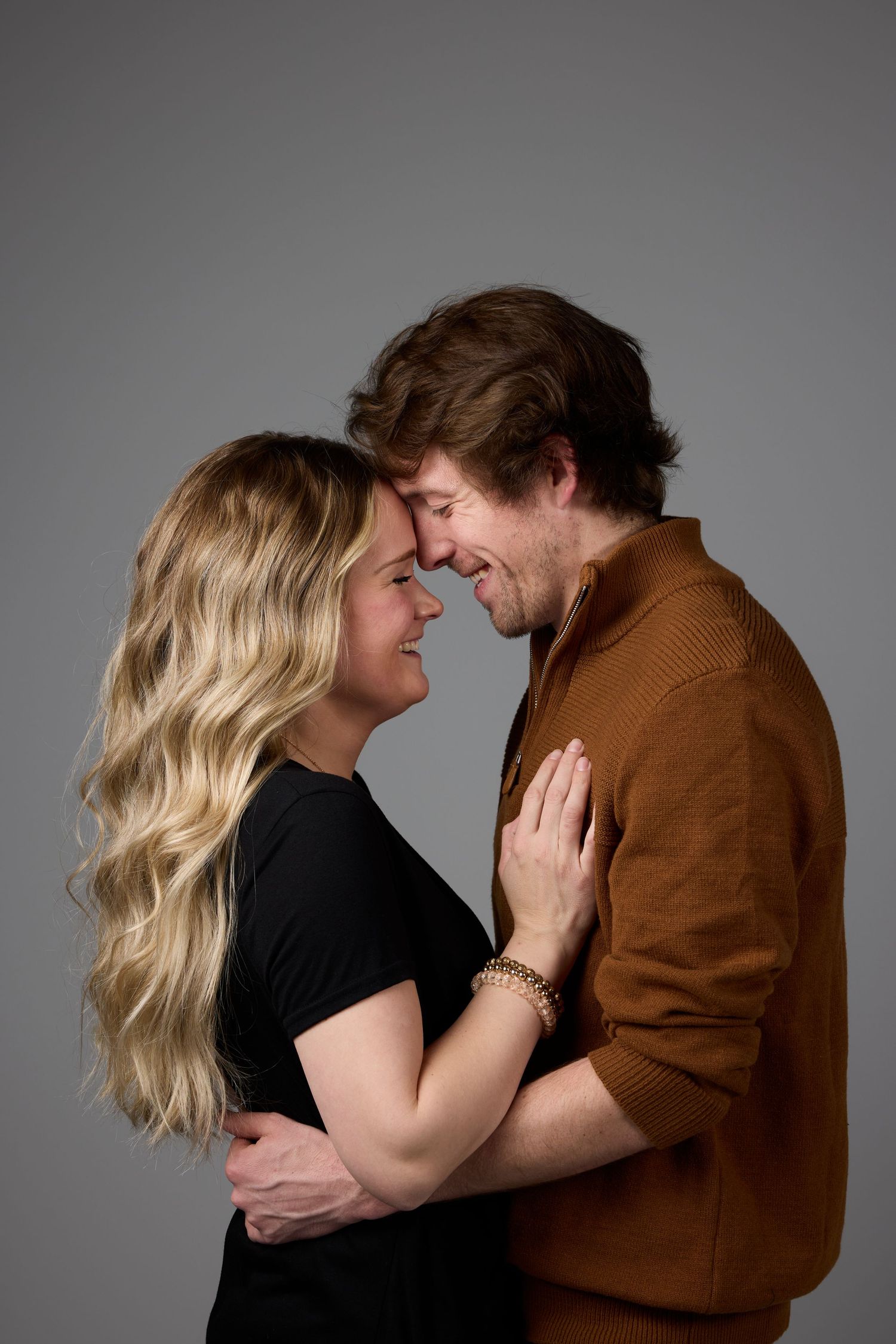 Romantic couple embracing in a series of intimate poses against a gray studio background.