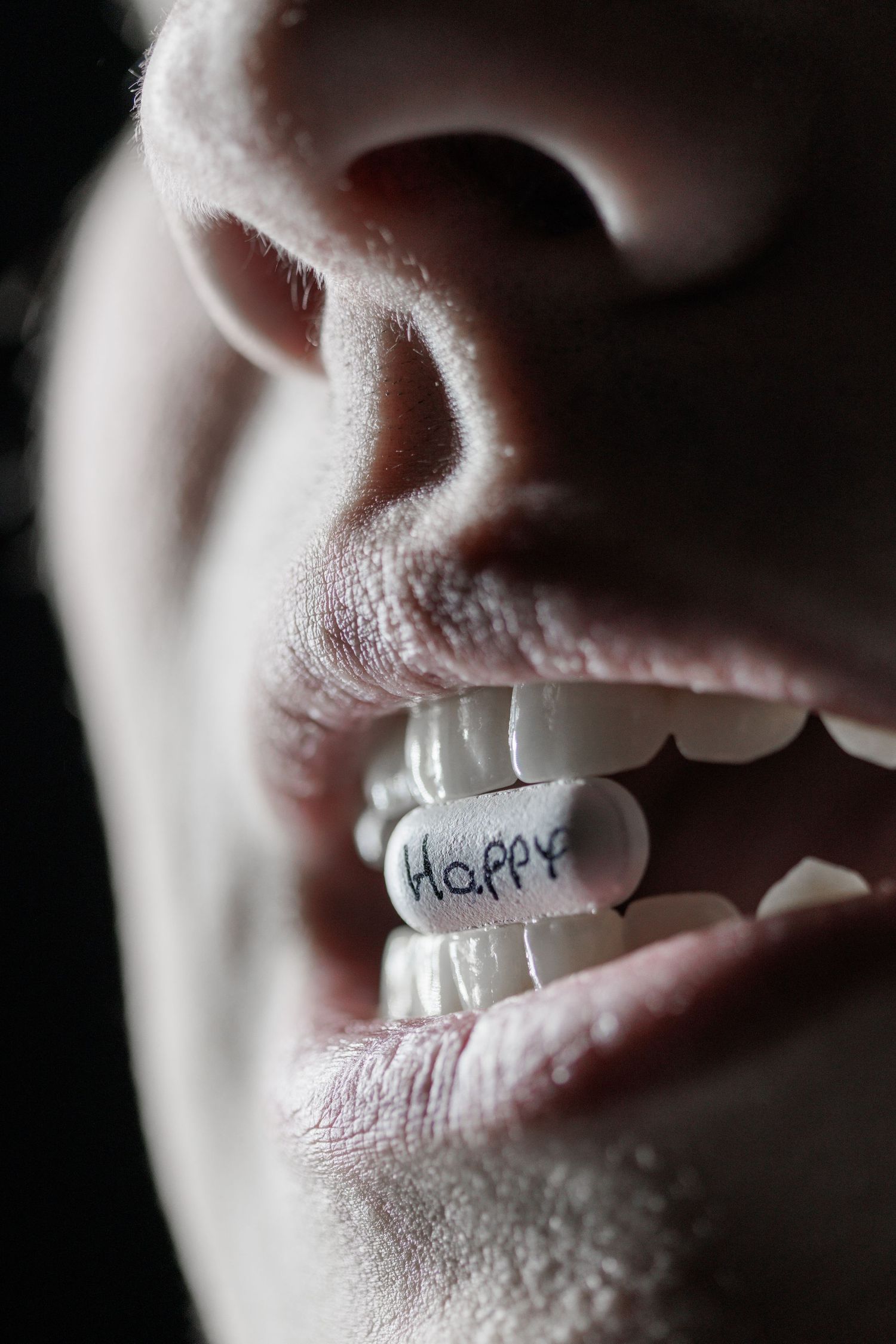 Extreme close-up of lips with the word 'Happy' written on a white strip.