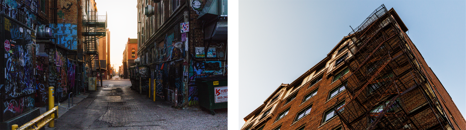 Urban street view between tall brick buildings with dramatic lighting and shadows.