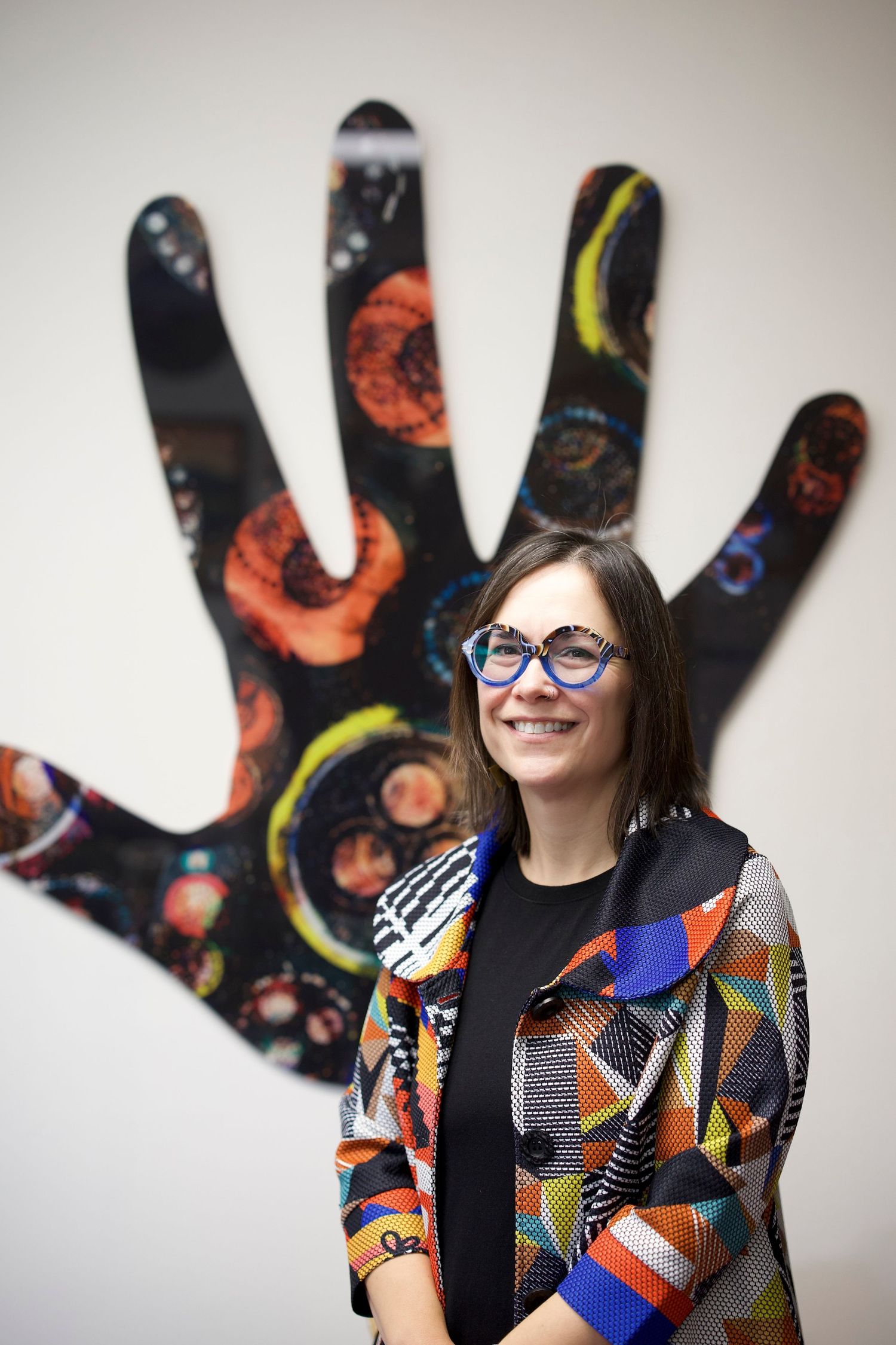 Person in colorful patterned outfit posing in front of abstract wall art.