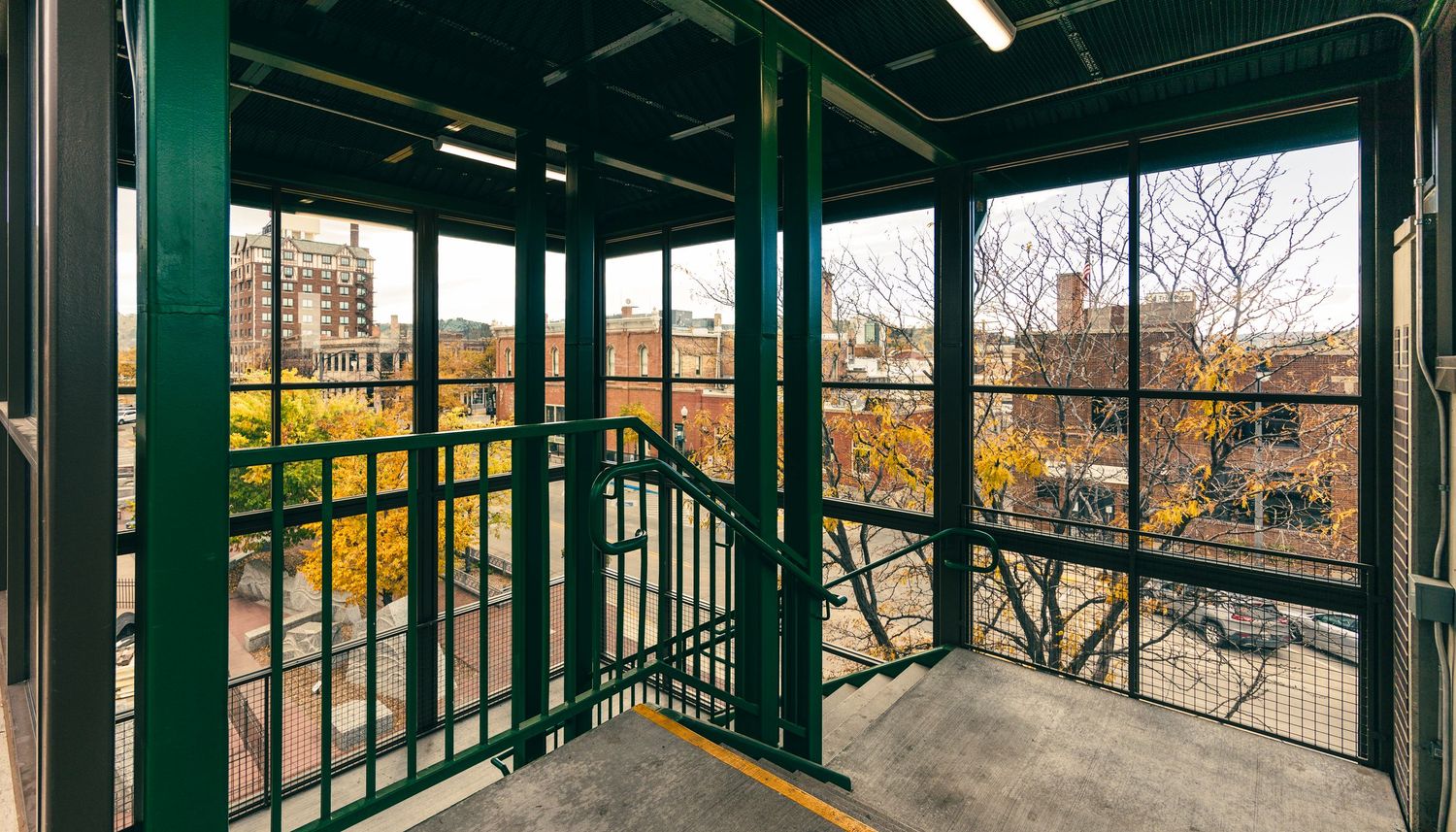 Interior view of a modern transit station platform with green support beams and large windows.