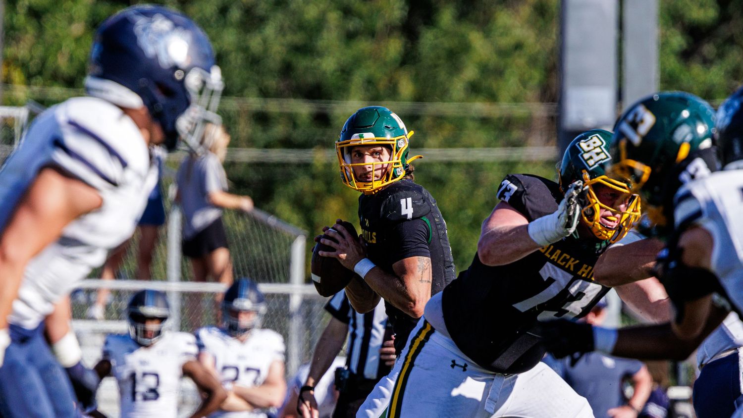 Football players in action during an outdoor game on a sunny field.