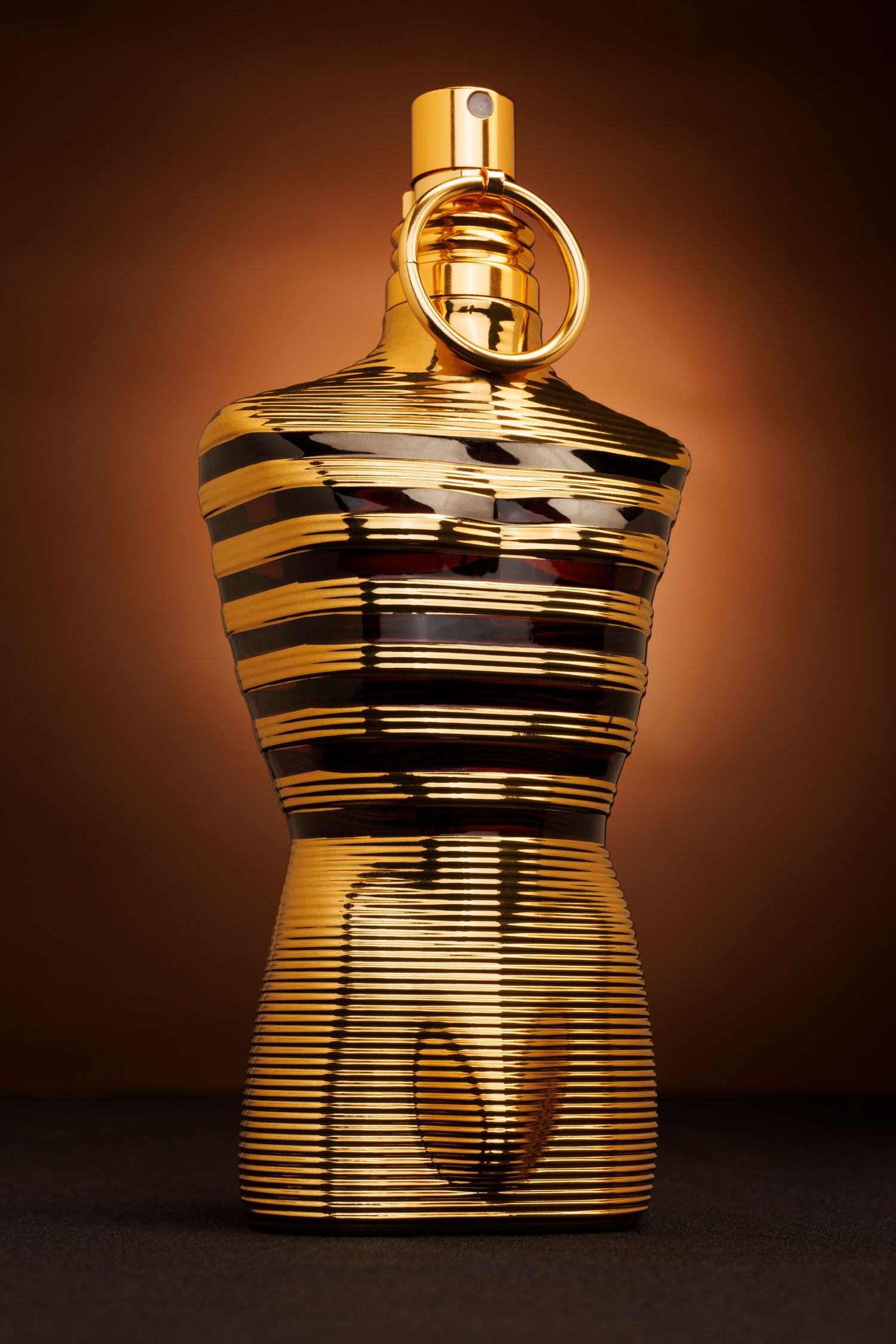 Gold metallic trophy or award with horizontal striped design against dark background.