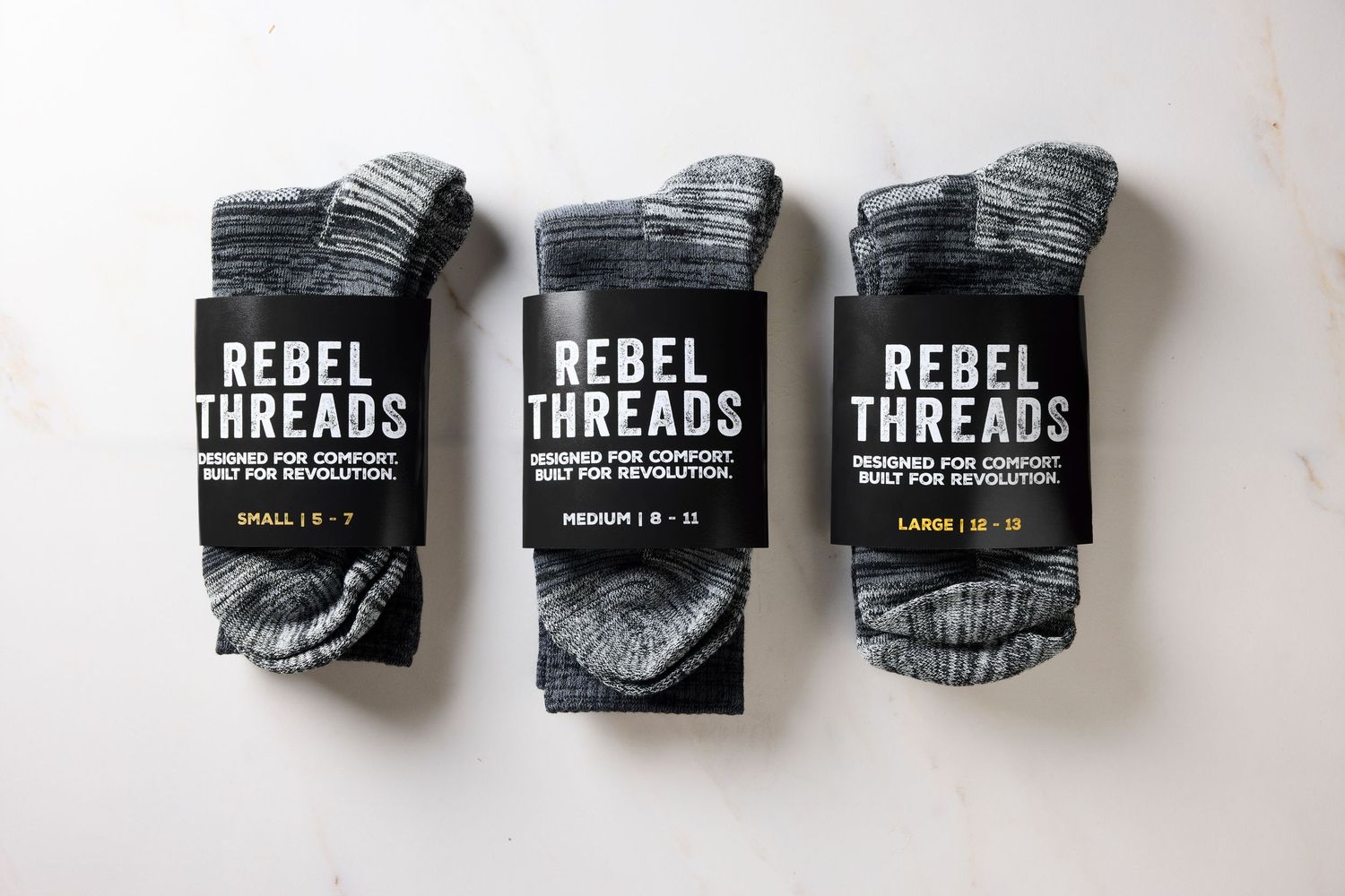 Folded black and gray socks with Rebel Threads branding displayed in a neat row against white background.