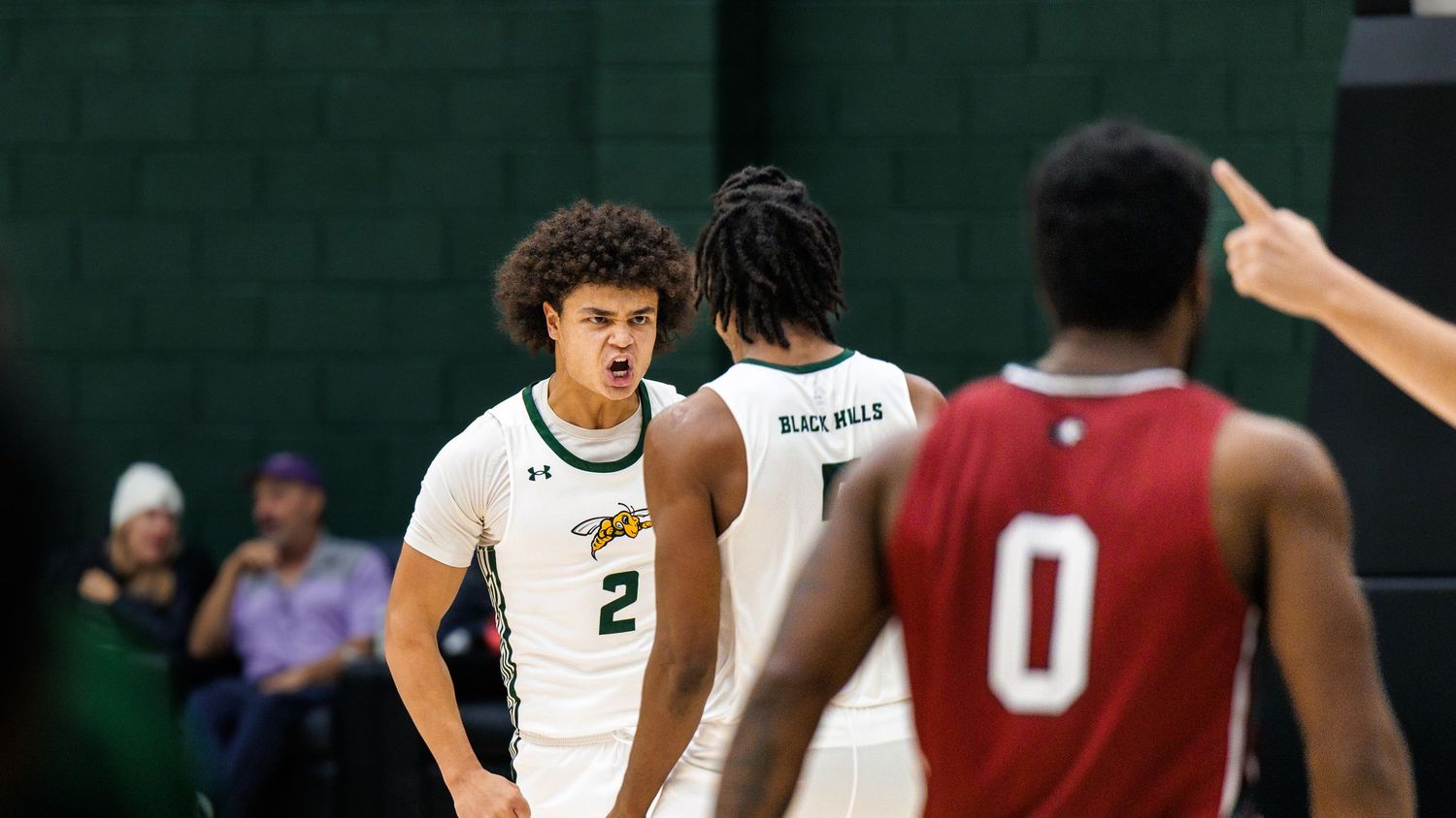 Basketball players compete for possession during an intense game on a green court.