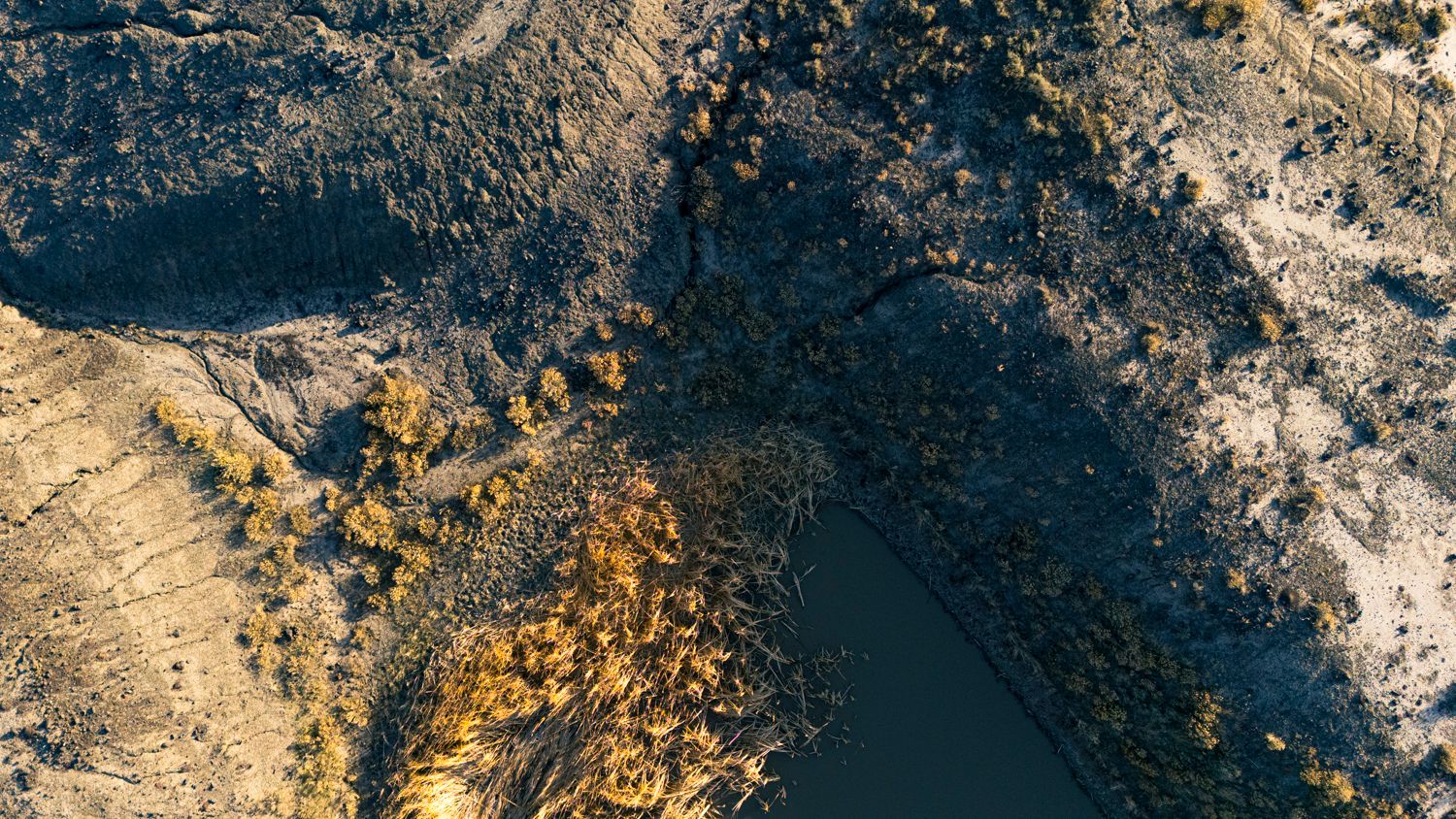 Aerial view of rocky mountain terrain with dramatic shadows and textures.