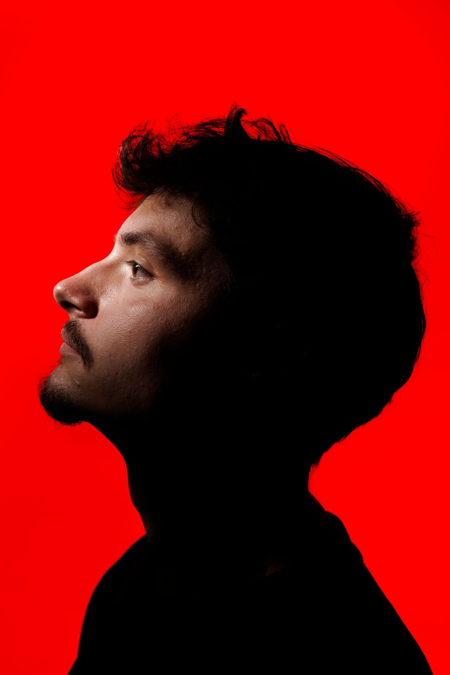 Dramatic silhouette profile shots against a vibrant red background showing different angles.