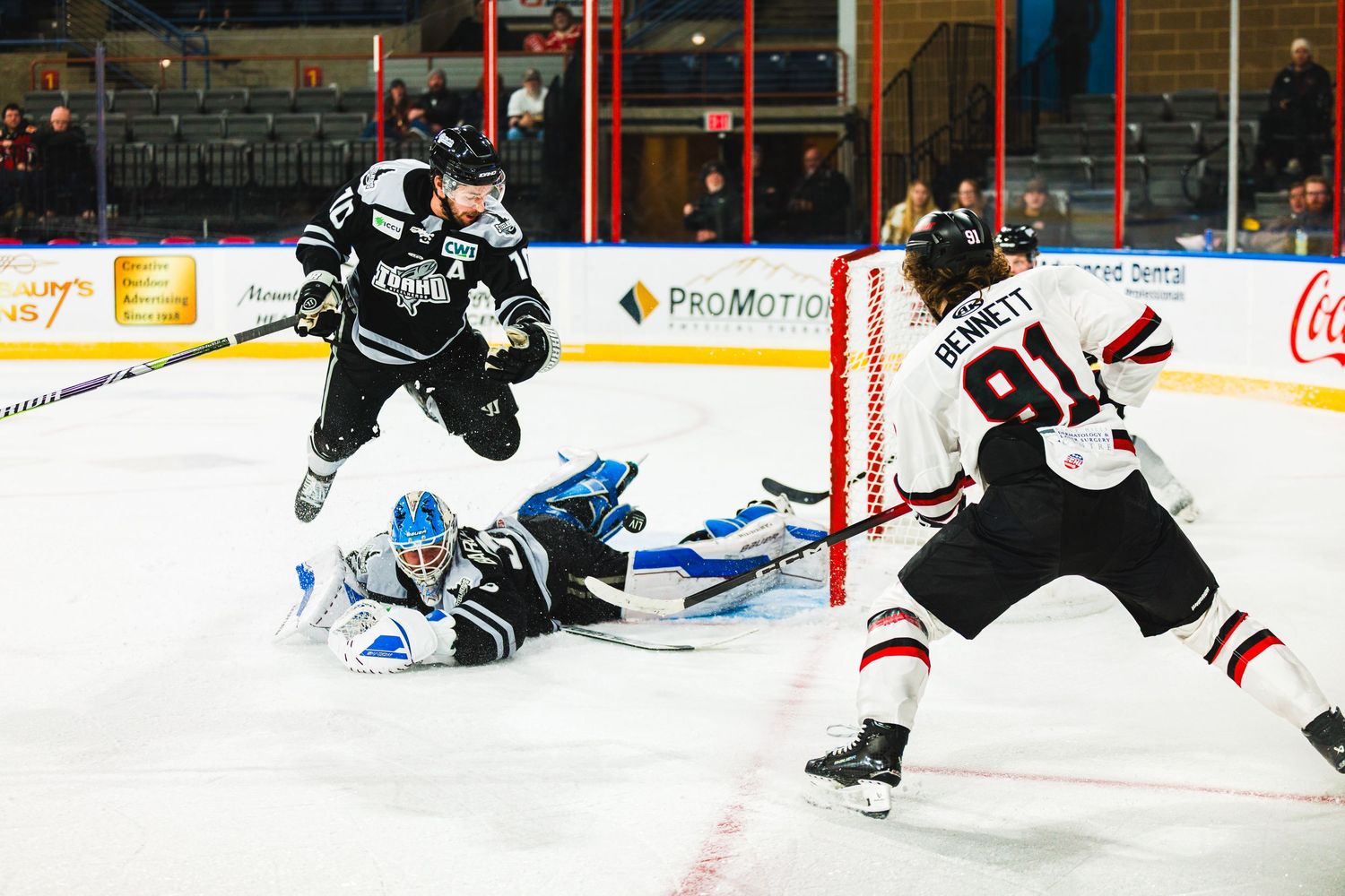 Hockey player takes a shot on goal during an intense game while goalie attempts to make the save.