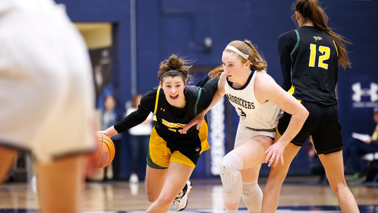 Basketball players compete for the ball during an intense indoor game match.