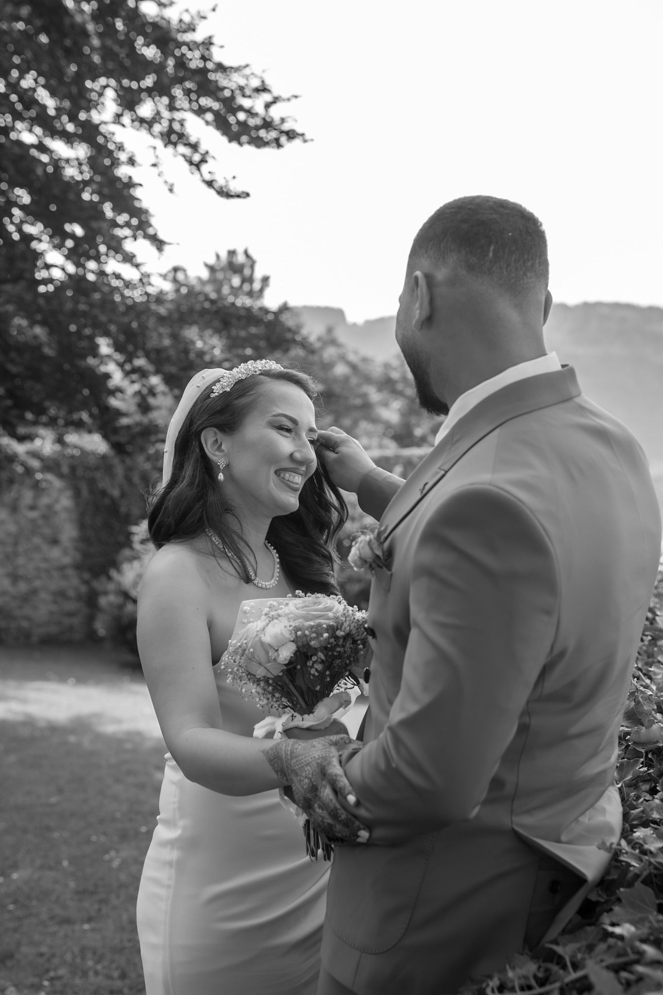A couple shares joyful moments during their outdoor wedding photoshoot in a natural setting.