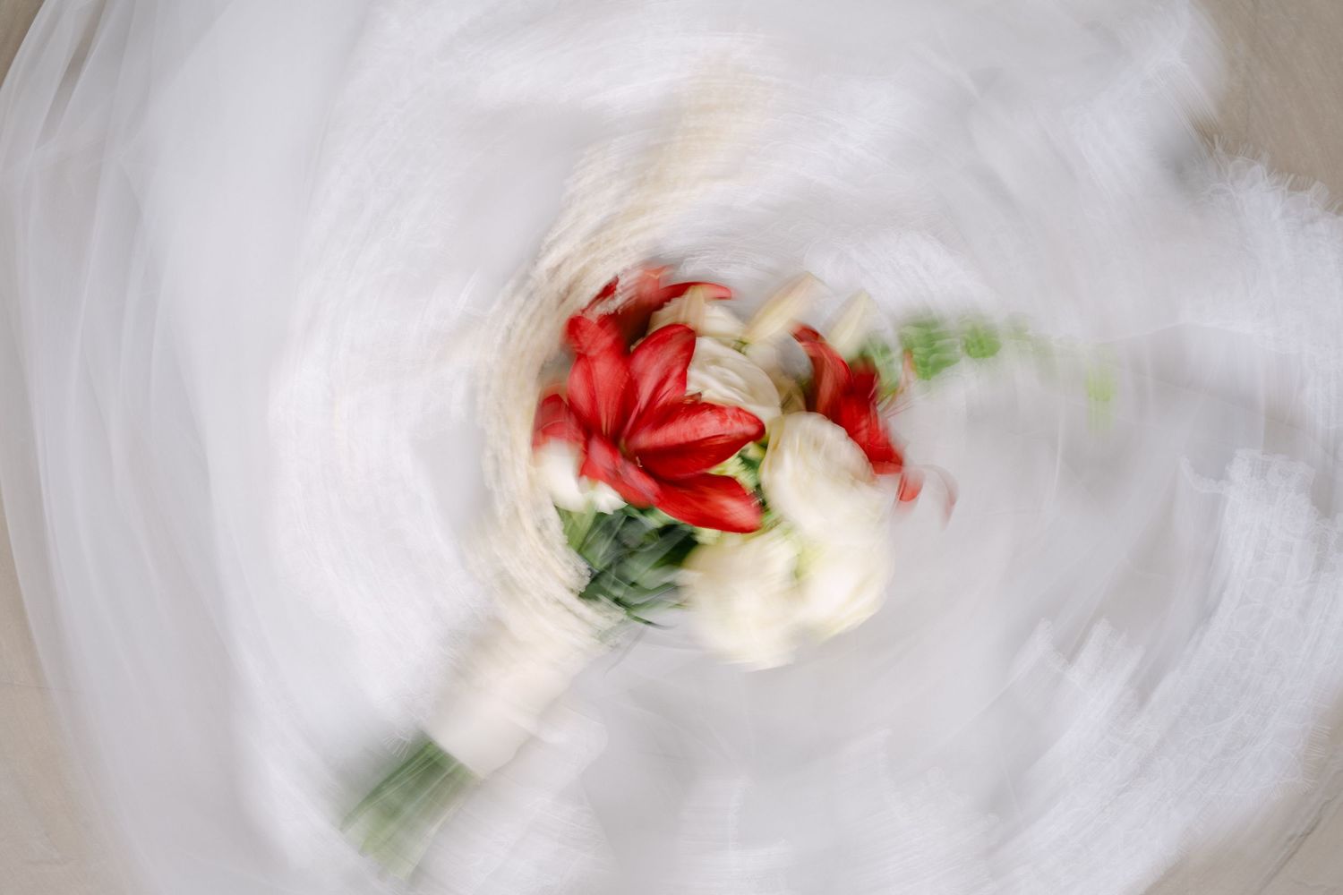 A spinning motion blur effect captures a vibrant red and white wedding bouquet in an artistic swirl.