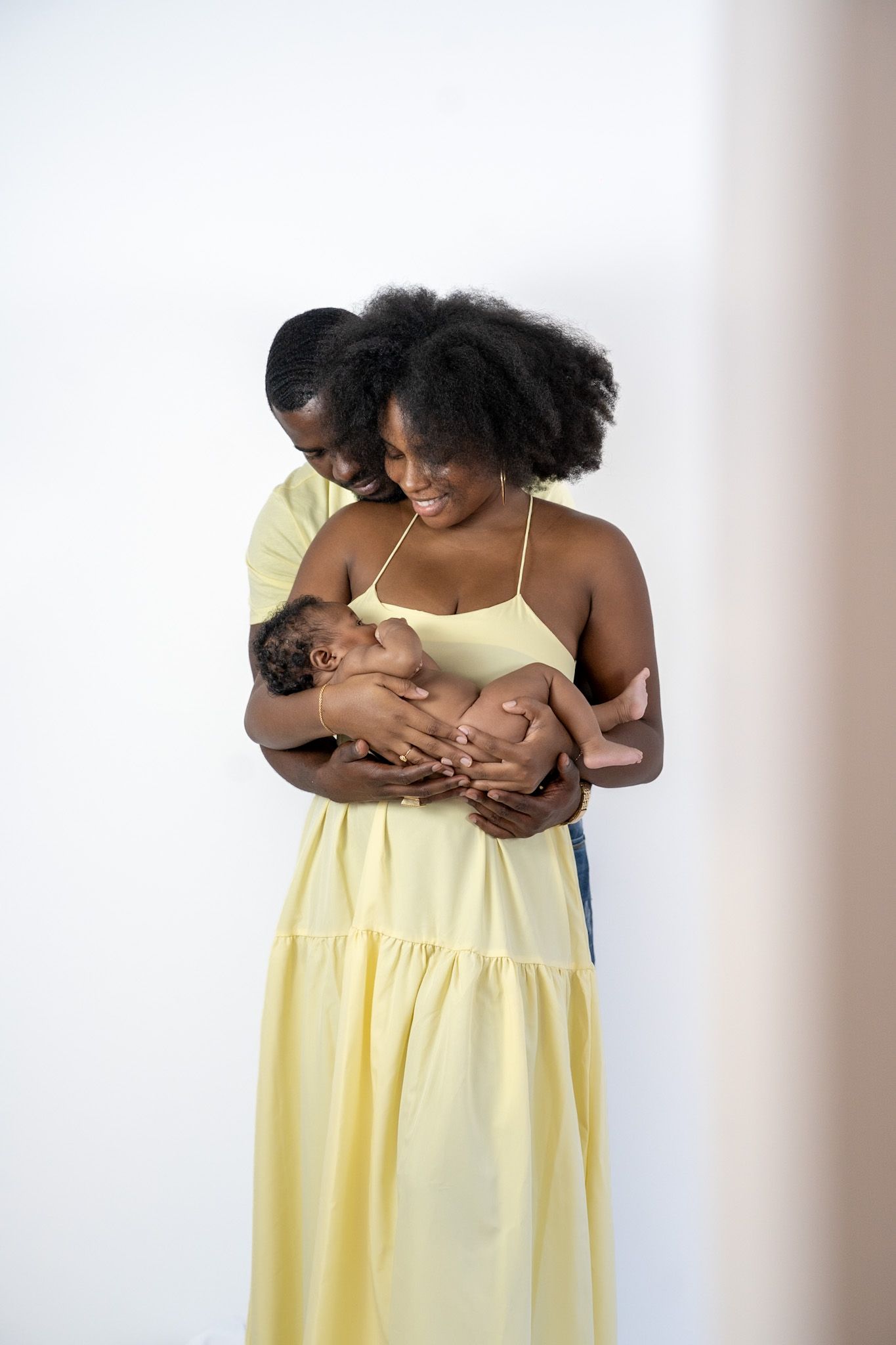 A series of tender moments captured between parent and baby in yellow dress against a light background.