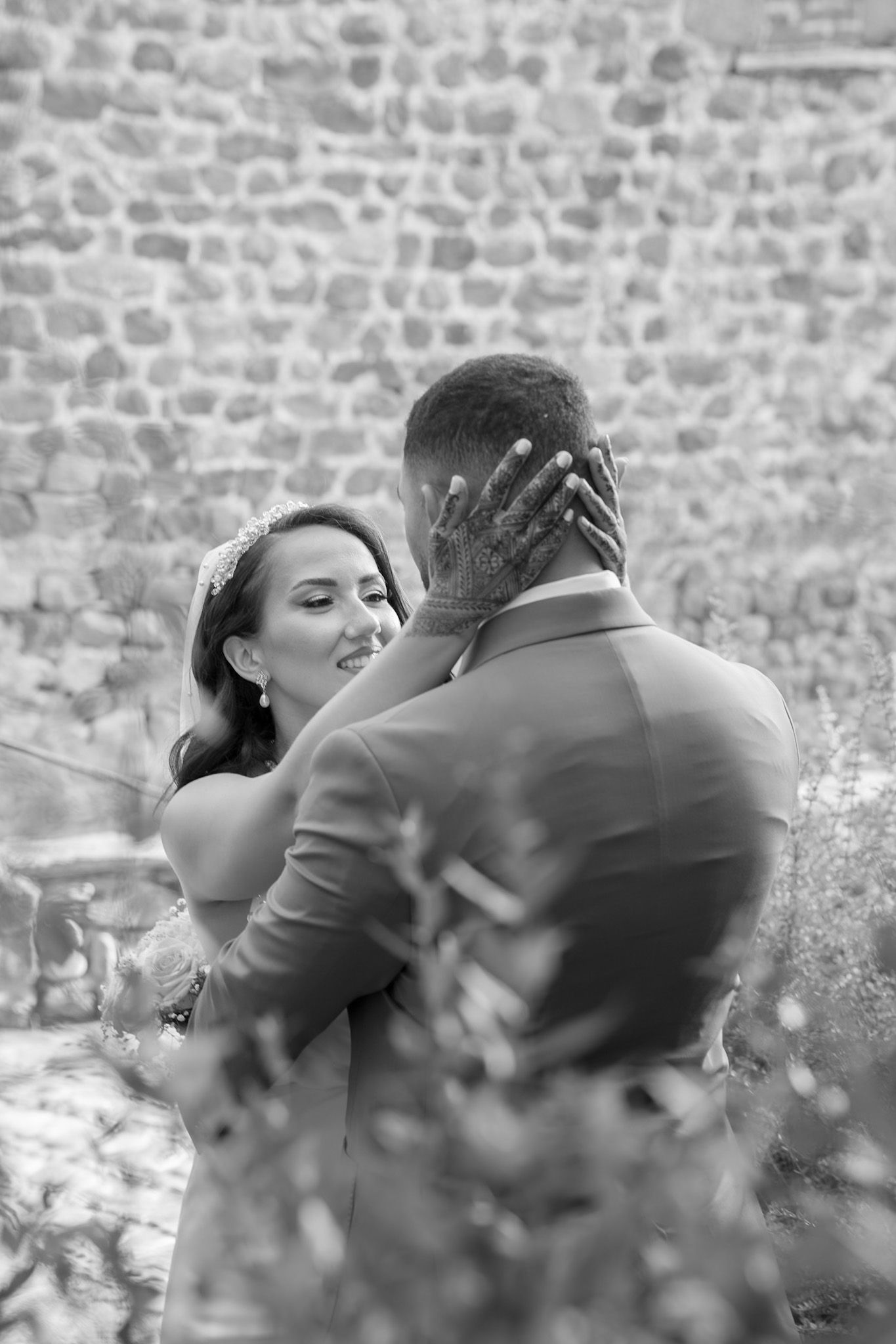 Un couple romantique s’embrasse et partage un moment tendre sur un fond de mur en pierre rustique.
