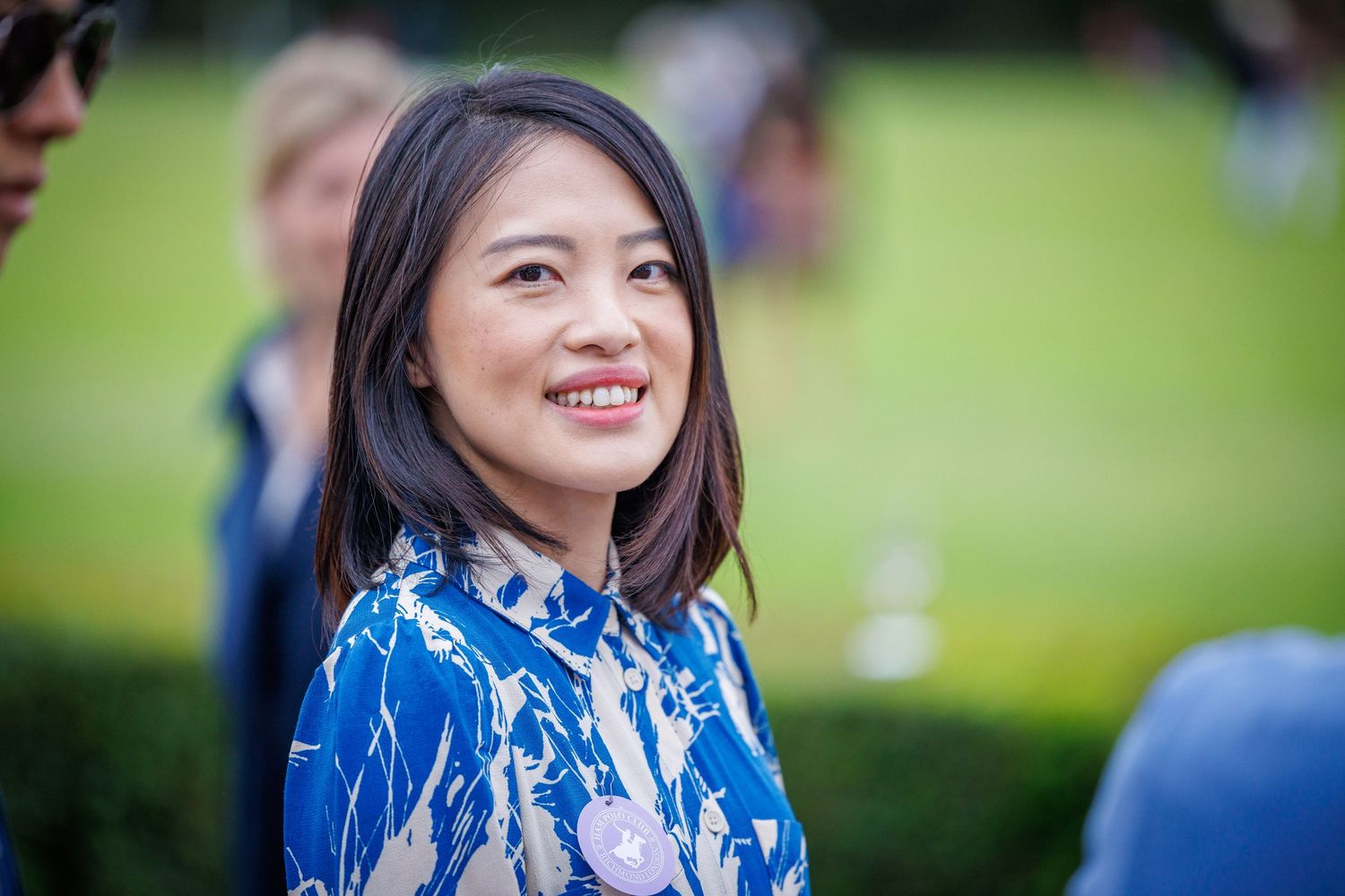 A portrait of a woman wearing a blue dress with a polo pitch in the background