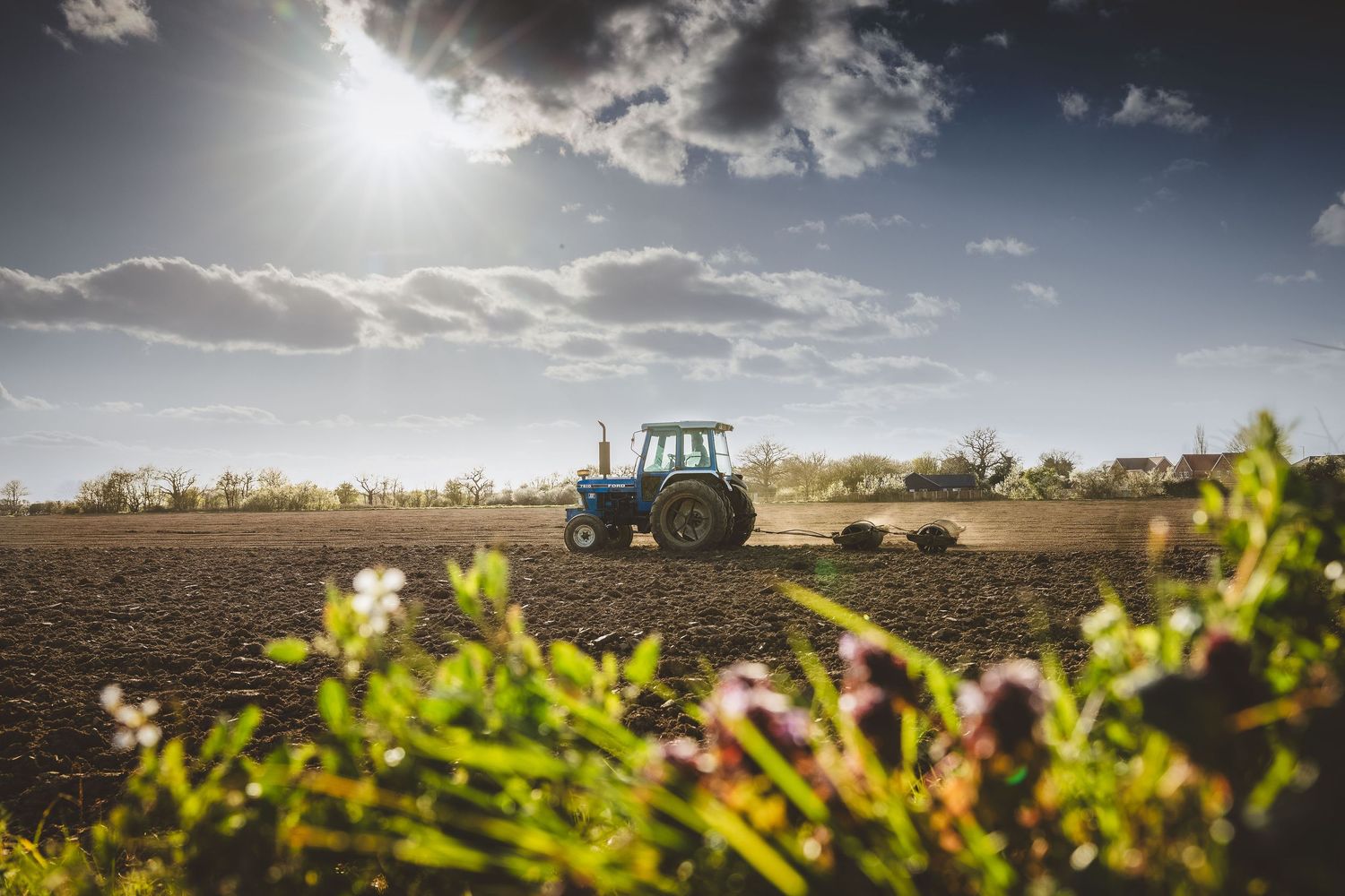 A tractor grading alone on a sunny afternoon