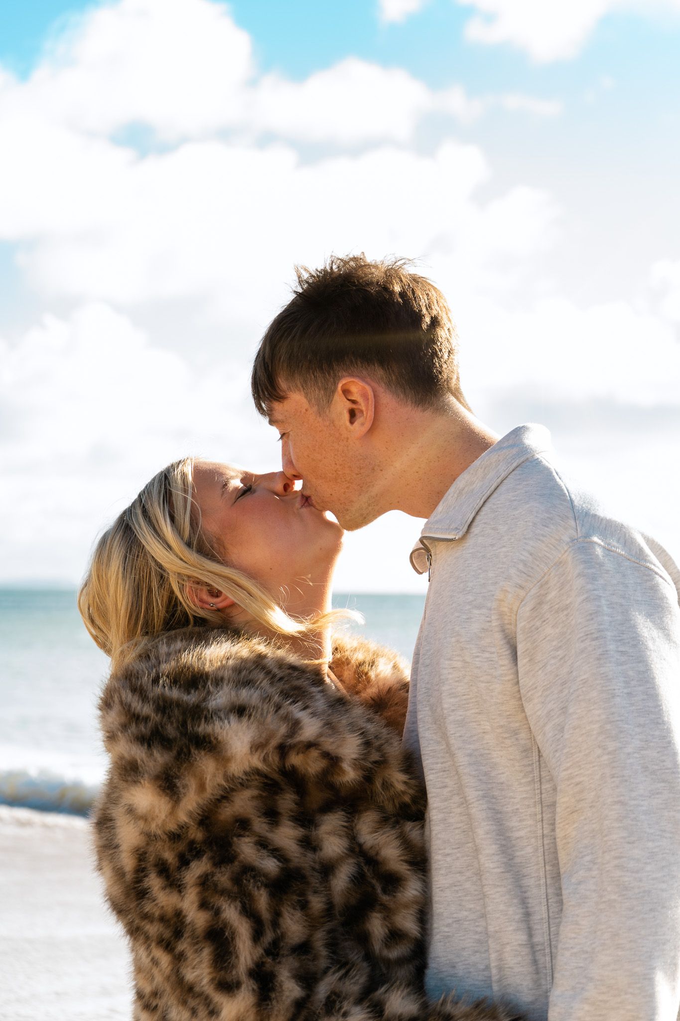 Dom and Cam kissing, the waves crash behind them.