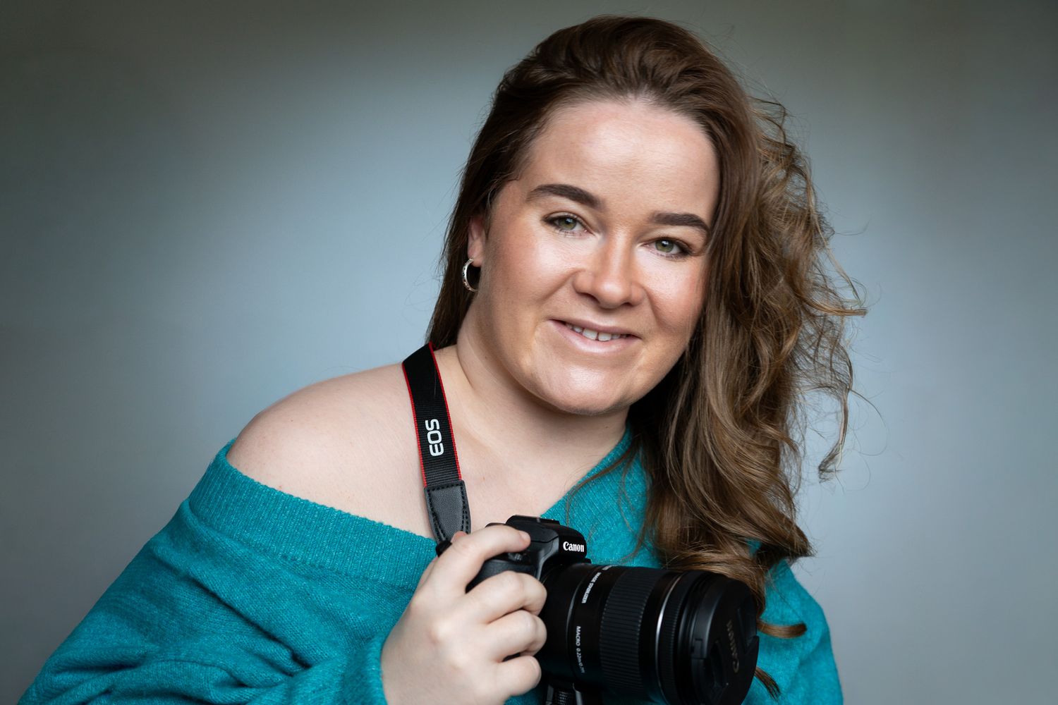 Dana, a white woman with long brown hair smiles joyfully at the camera.