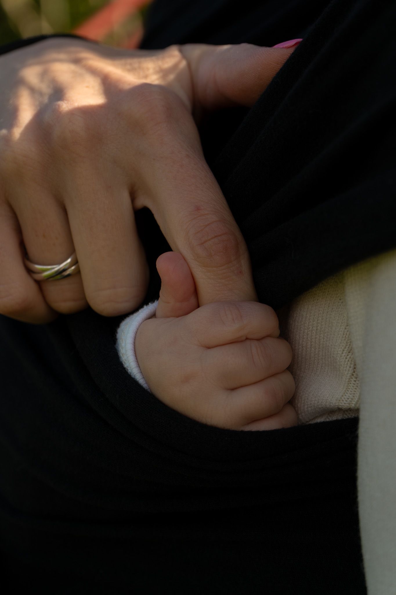 An adult hand and baby hand embracing