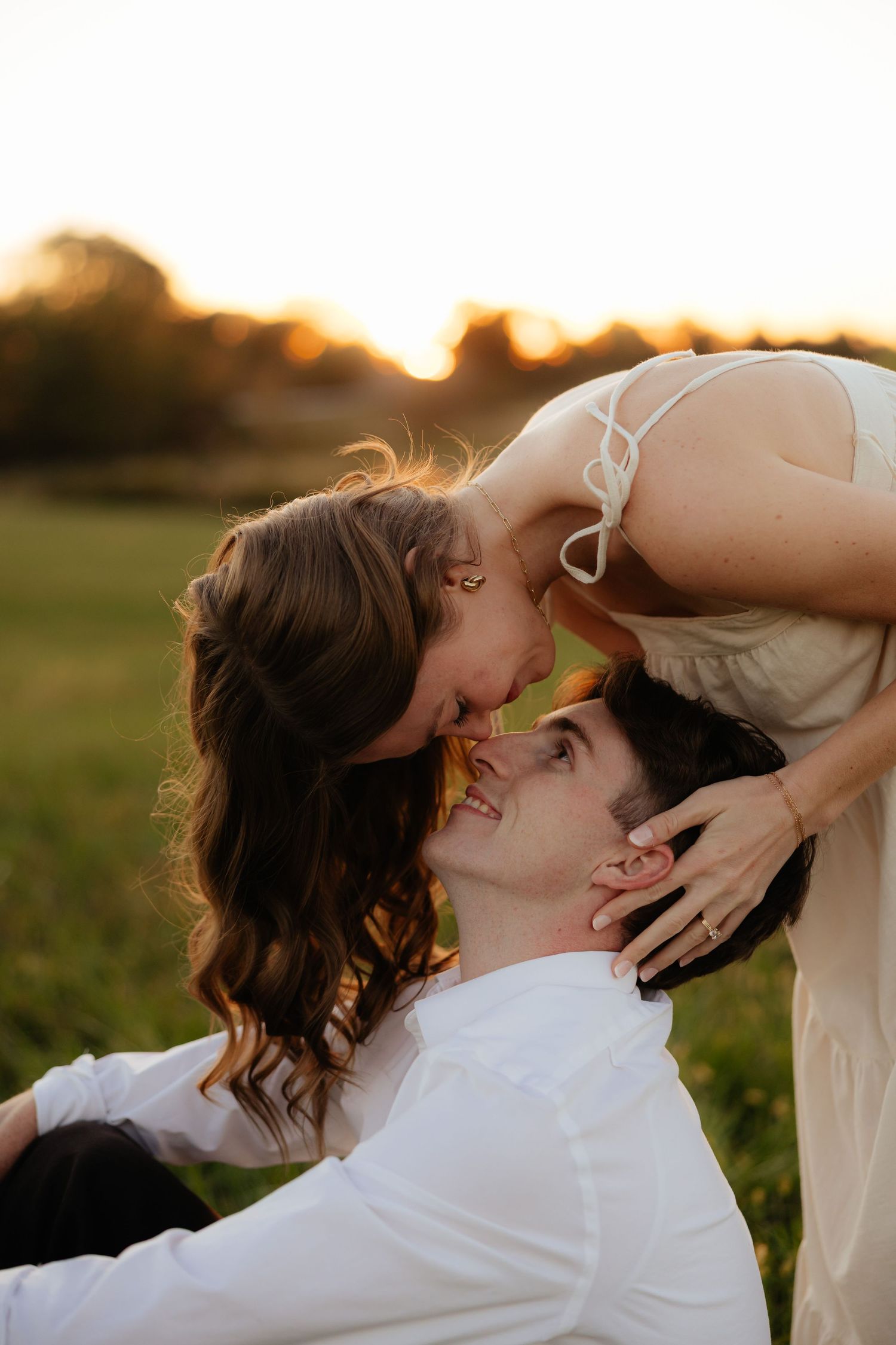 Romantic sunset portrait in a grassy field with warm golden light.