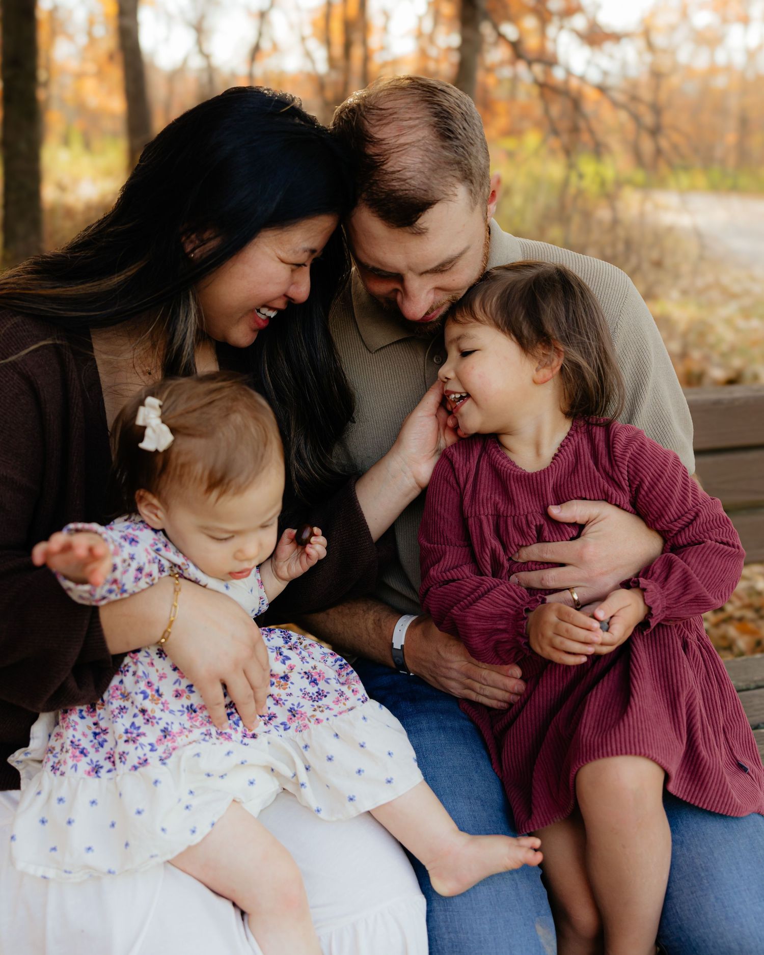 Family sharing intimate moment together on bench during autumn photoshoot.