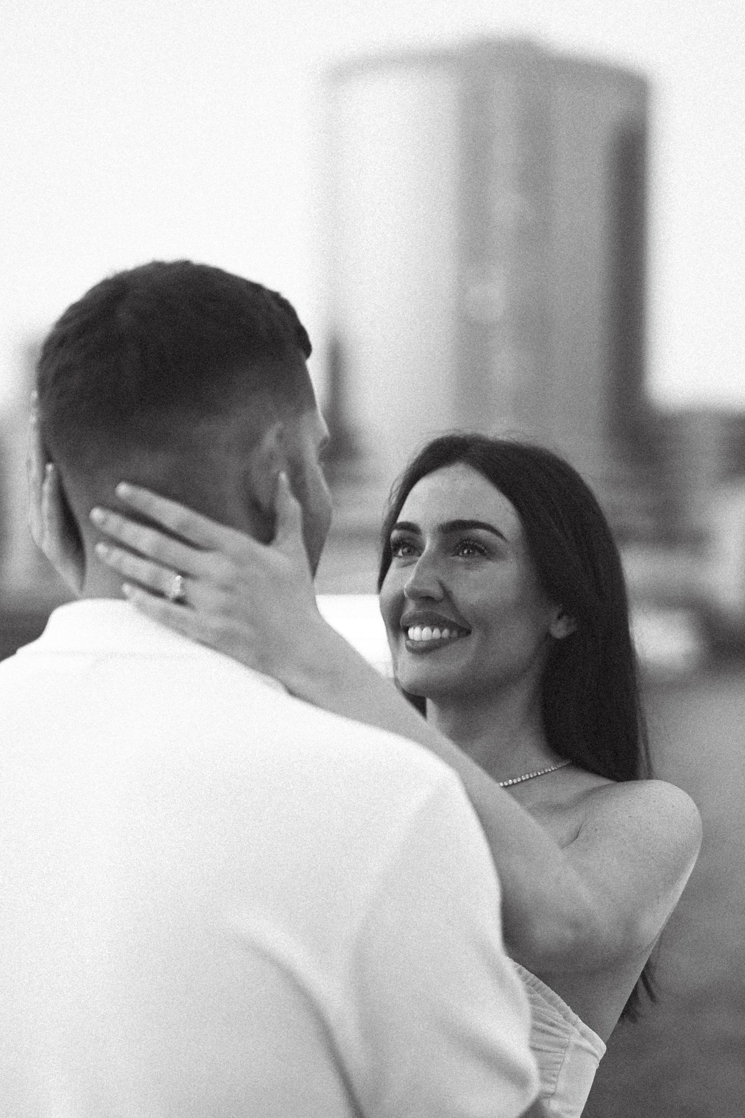 A romantic black and white moment between a couple against a cityscape background.