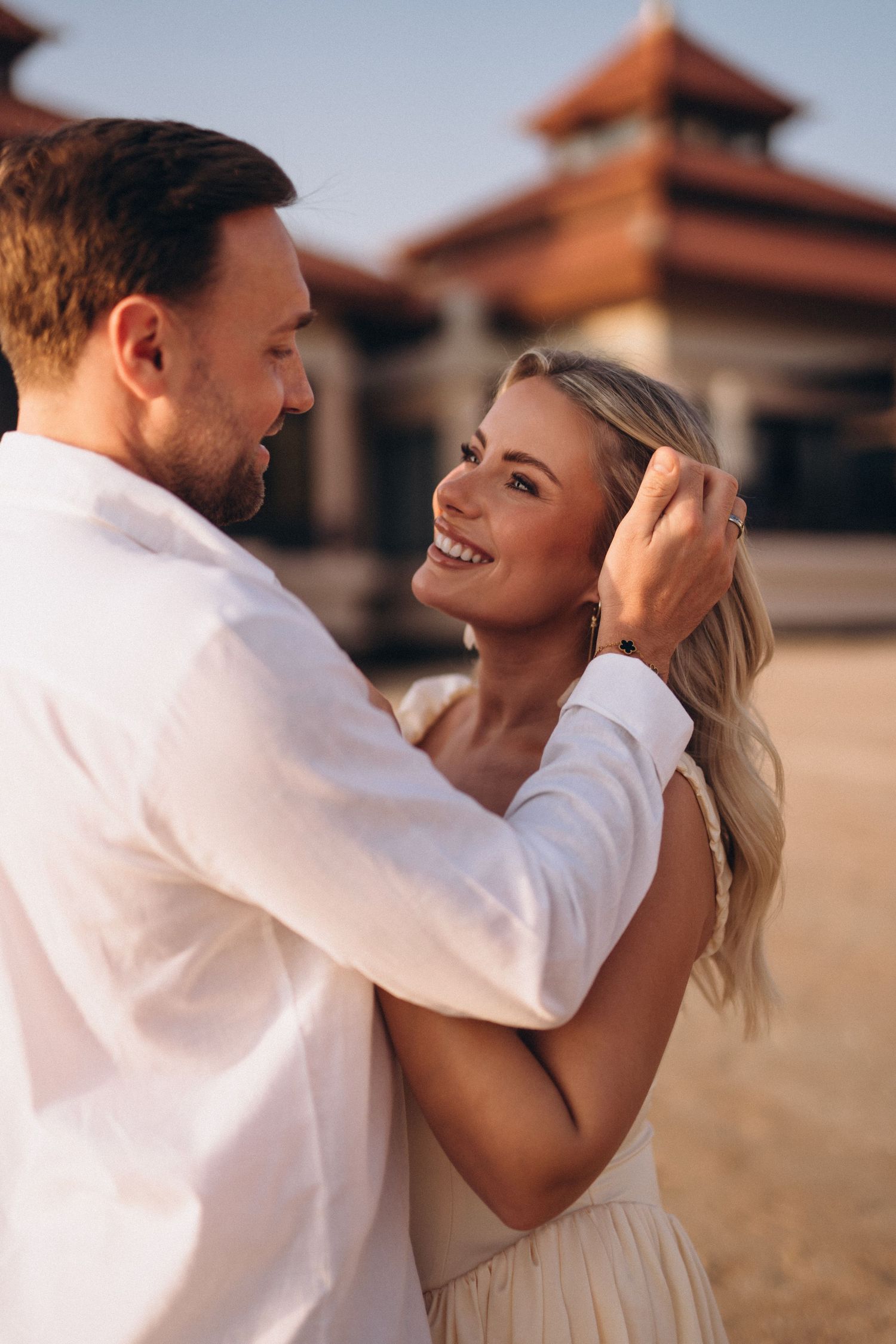 Intimate couple moment captured in front of ornate Asian building architecture.