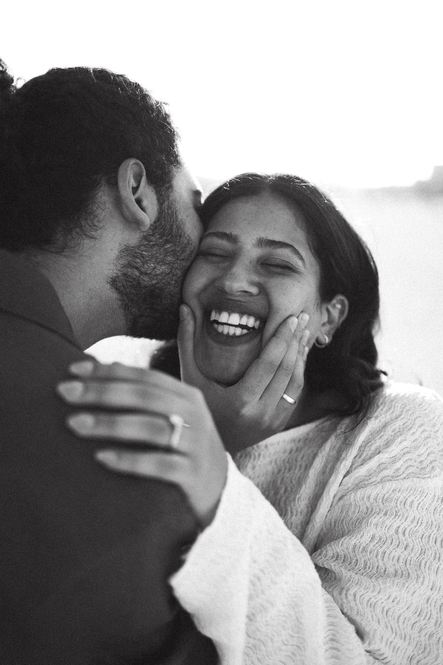 A candid black and white photo capturing a joyful moment between a couple.