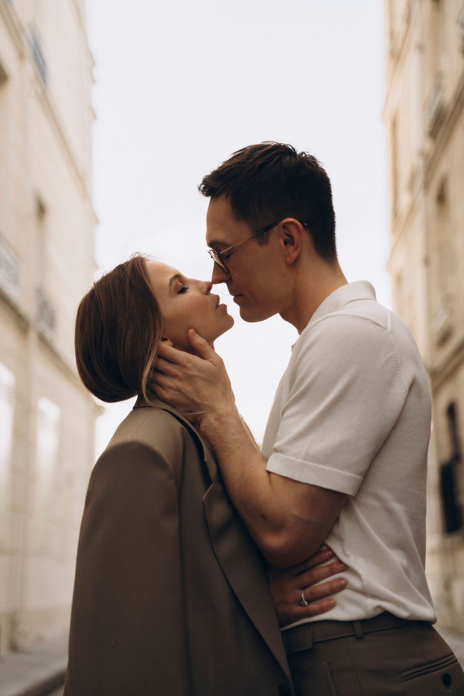 Romantic couple sharing an intimate moment on a European city street, man gently holding womans face.