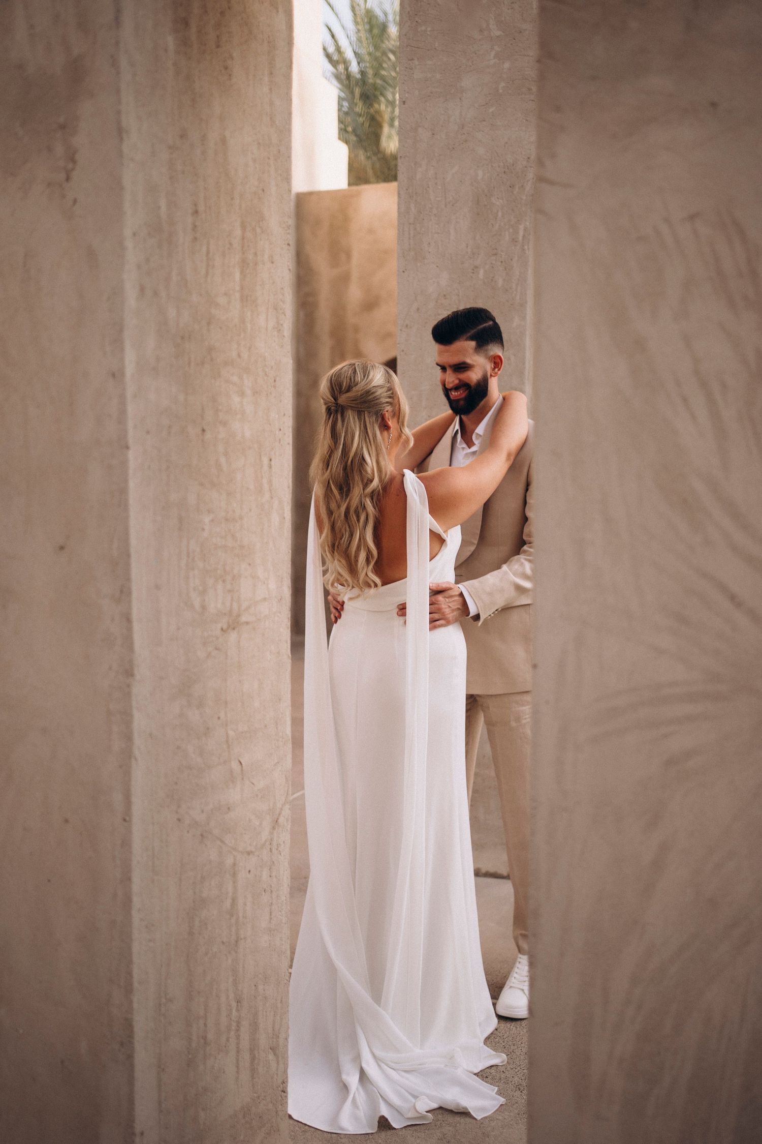 A couple shares an intimate first look moment against concrete pillars in a romantic wedding sequence.