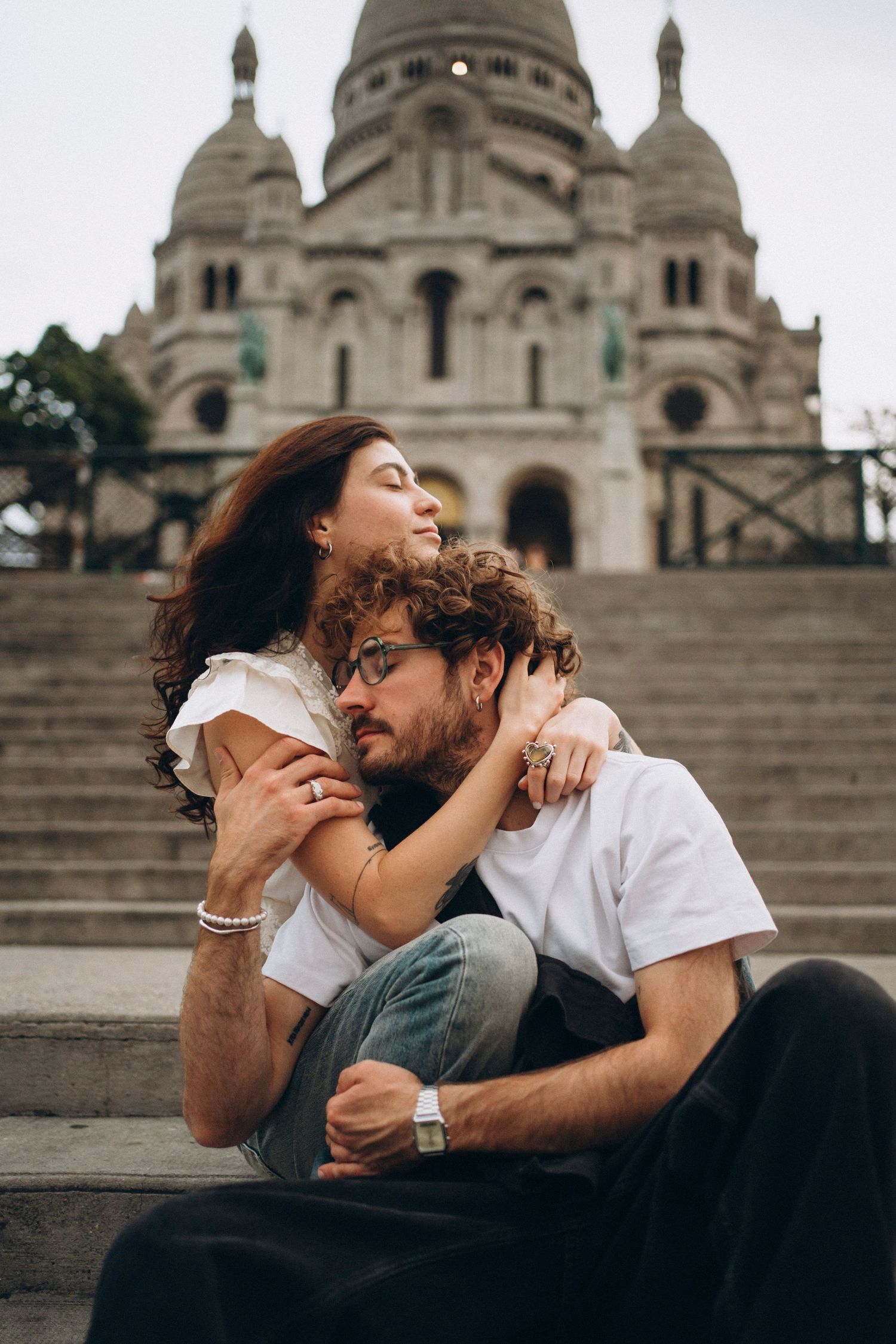 Romantic couple embracing on steps of Sacré-Cœur Basilica in Montmartre, Paris, France.