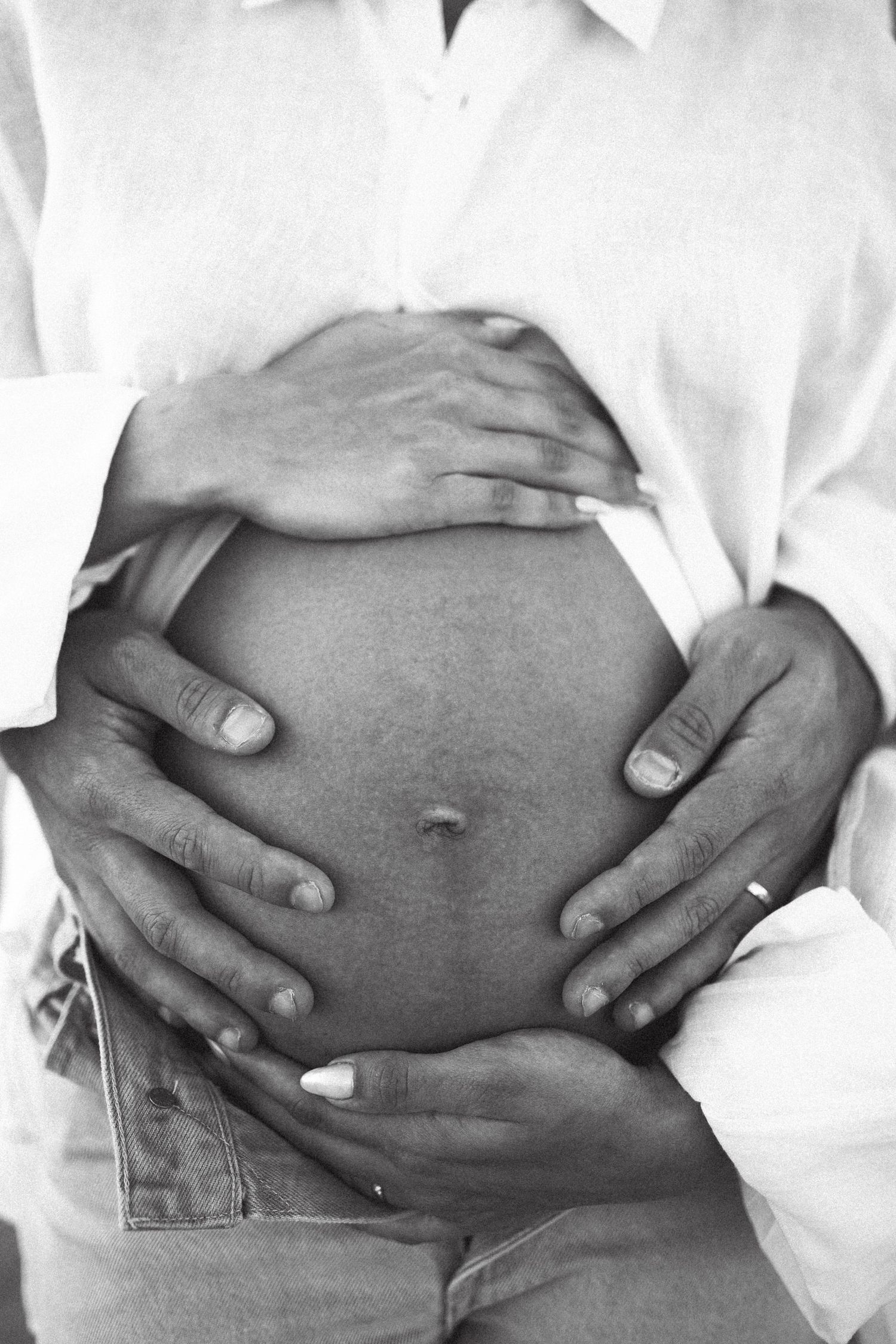 Black and white close-up of hands cradling a pregnant belly.