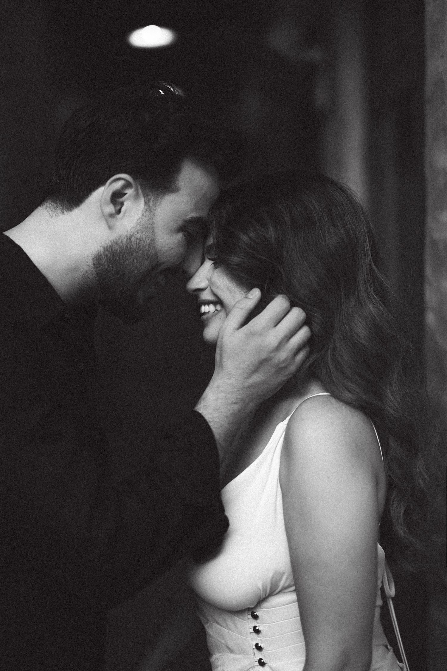 An intimate black and white portrait of a couple sharing a tender moment.
