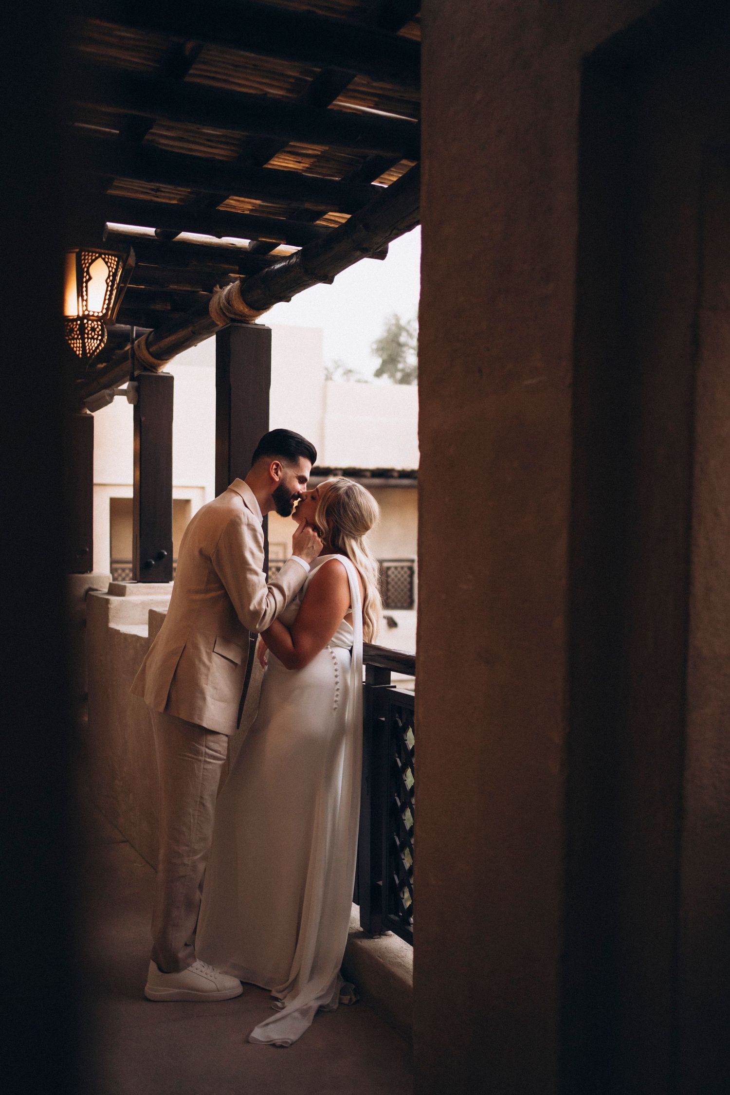 A couple sharing an intimate moment under a rustic covered walkway at dusk.