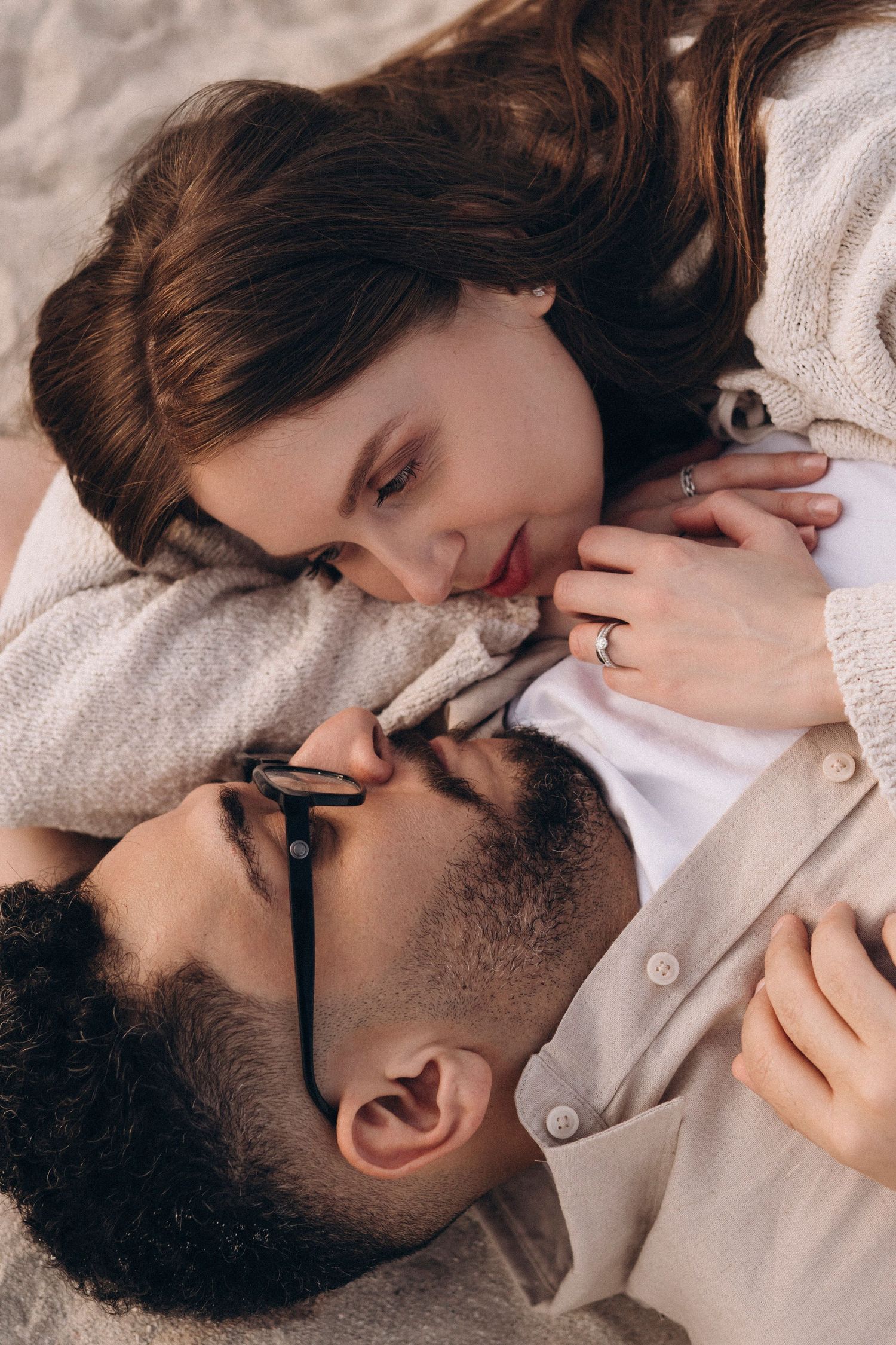 Close-up of couple lying on sandy beach showing affection.